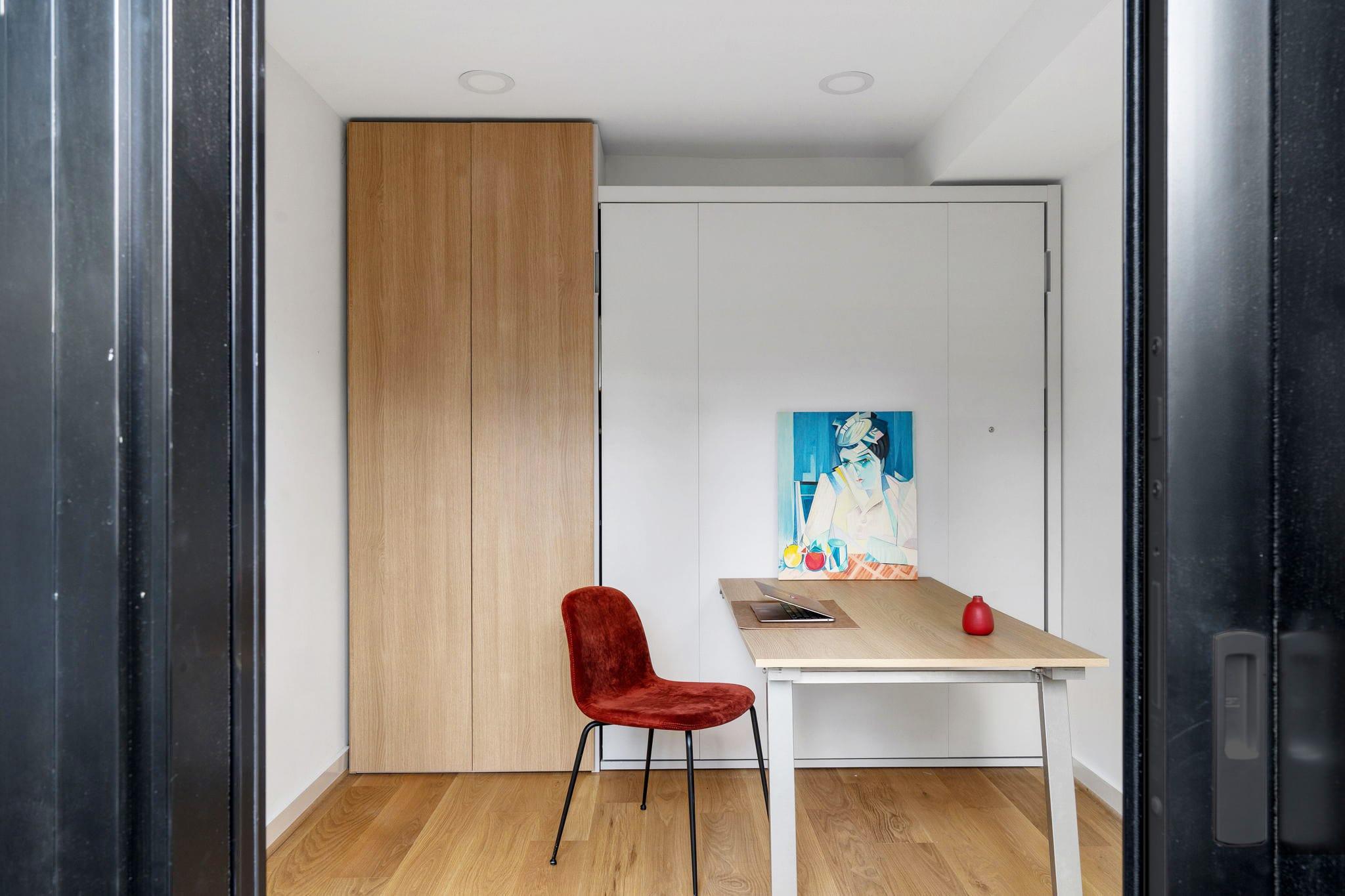 Oak wall unit closed beside a desk with a red chair