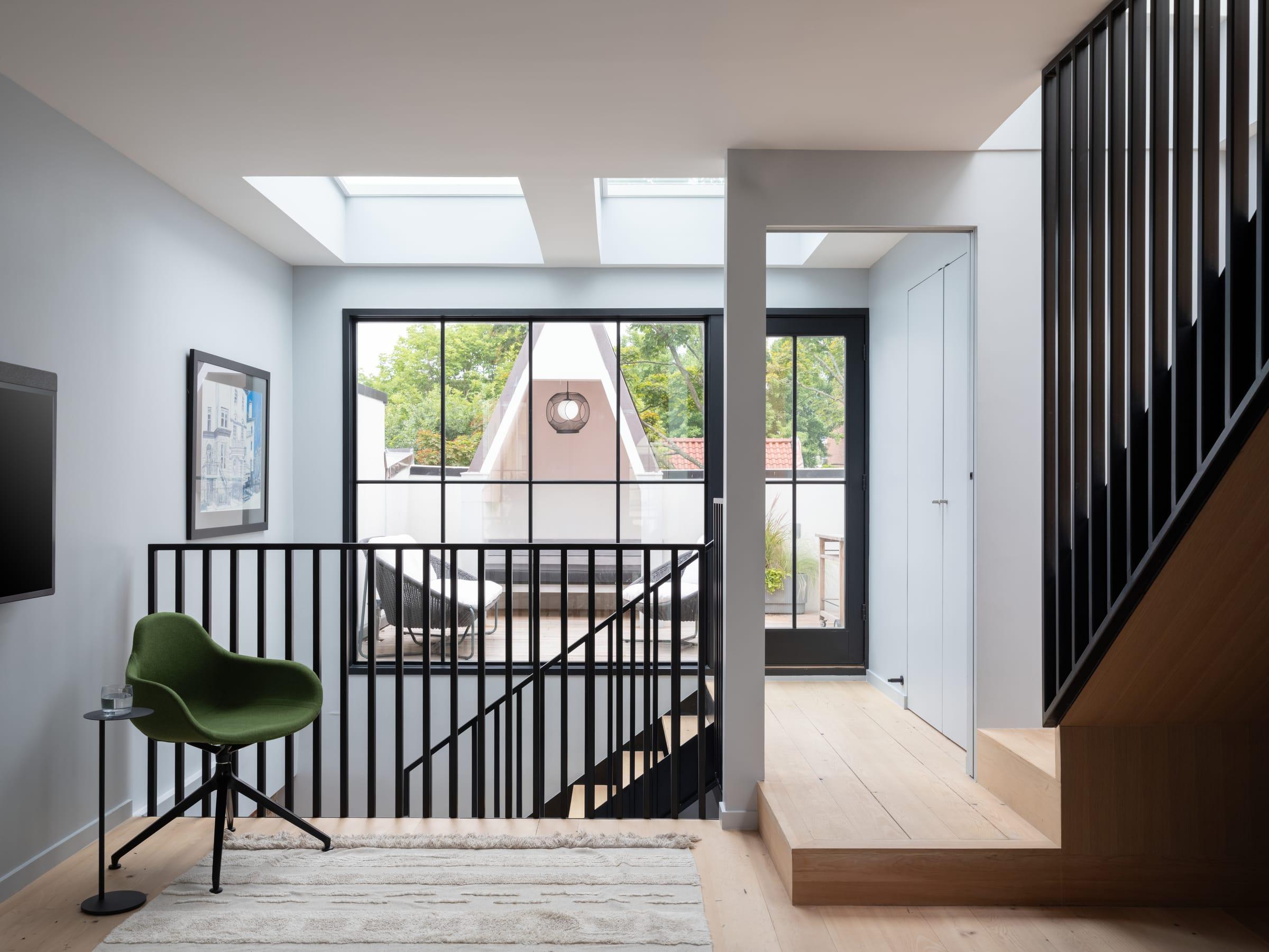 Landing with a green chair under a skylight and black railings