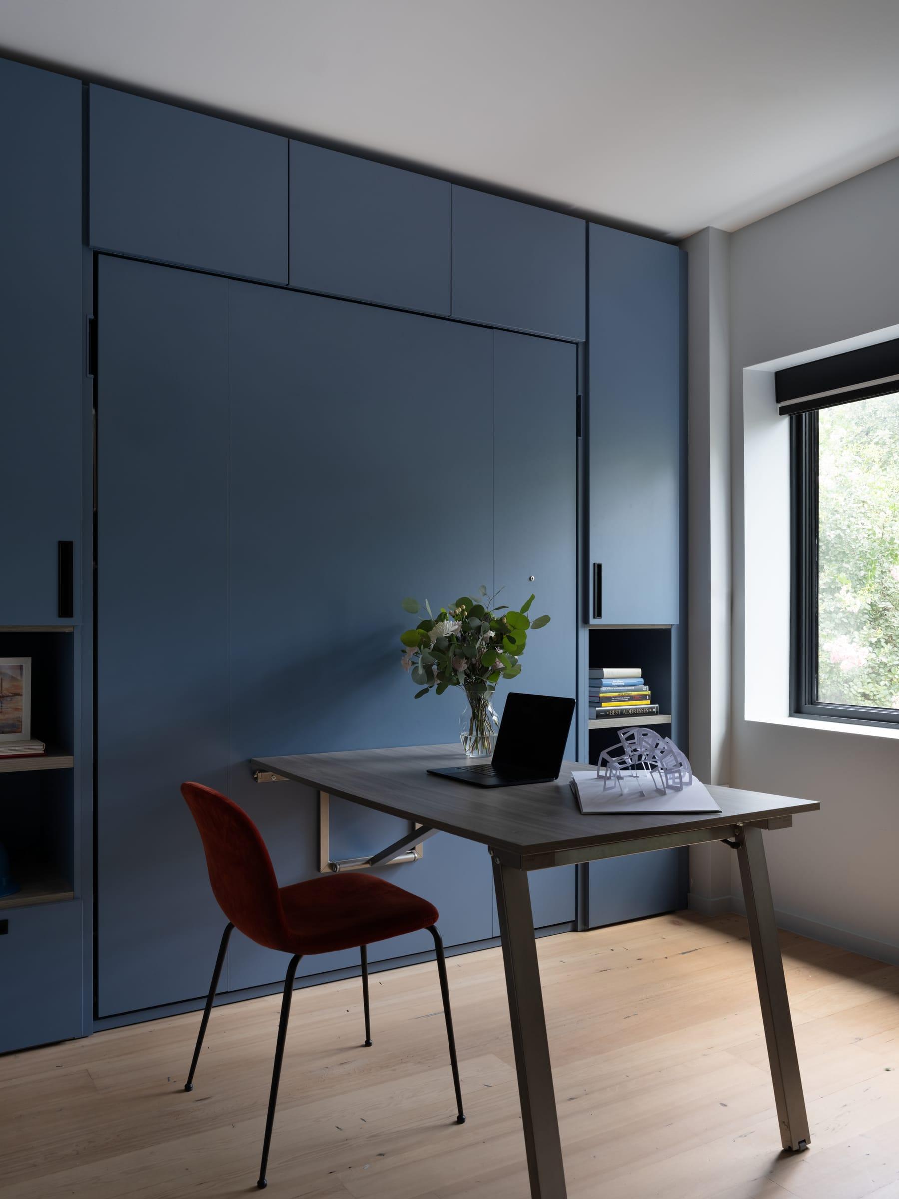 Blue wall unit with a desk and a red chair