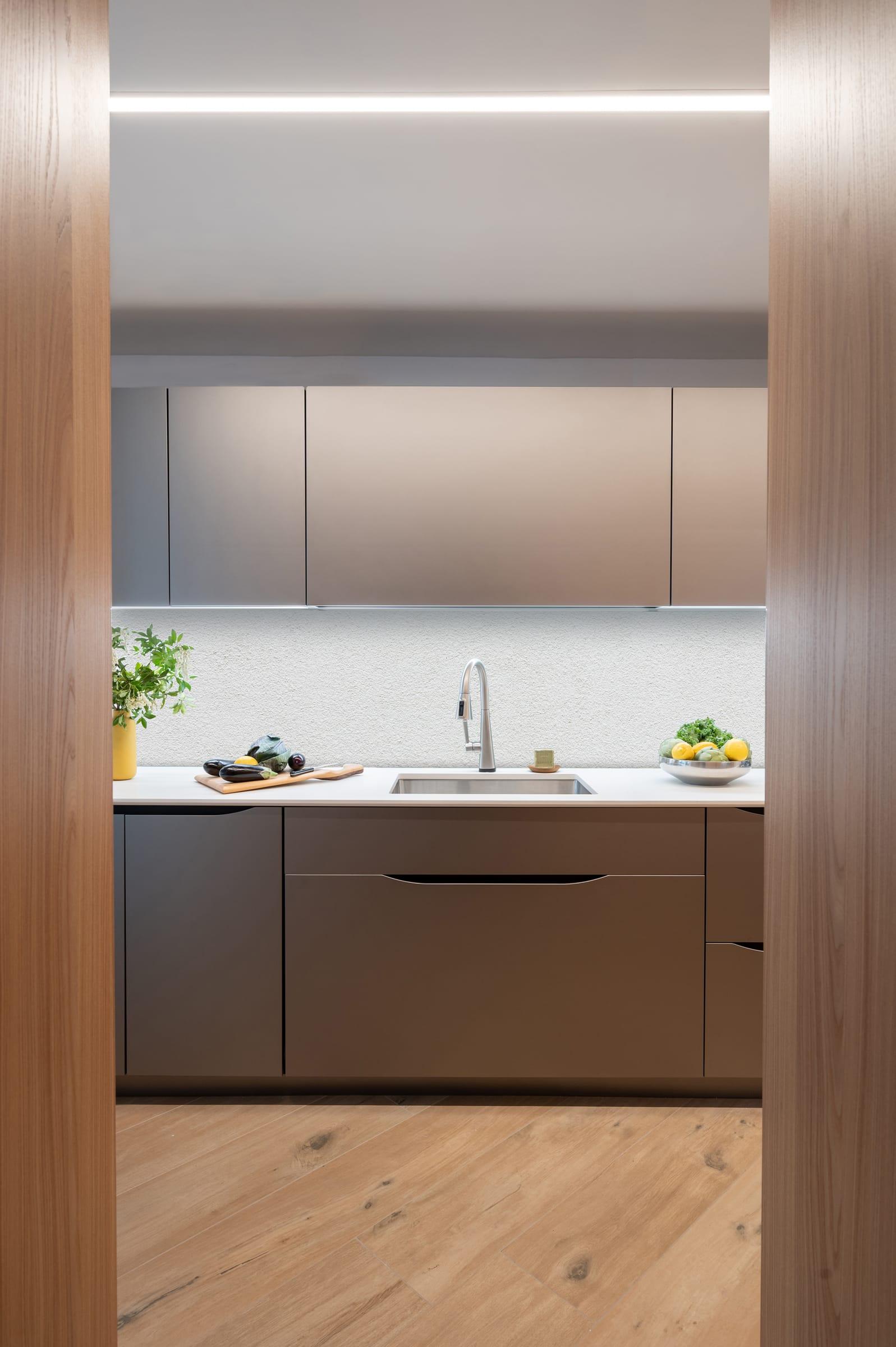 Grey kitchen framed in wood, a lit shelf under the wall cabinets