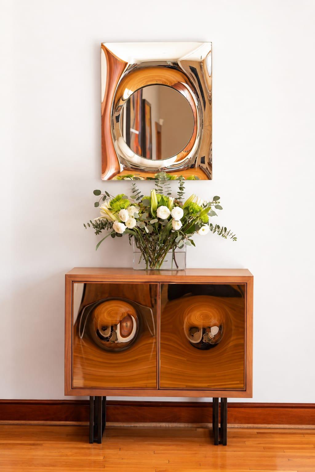 Walnut cabinet with round panels under a brass mirror