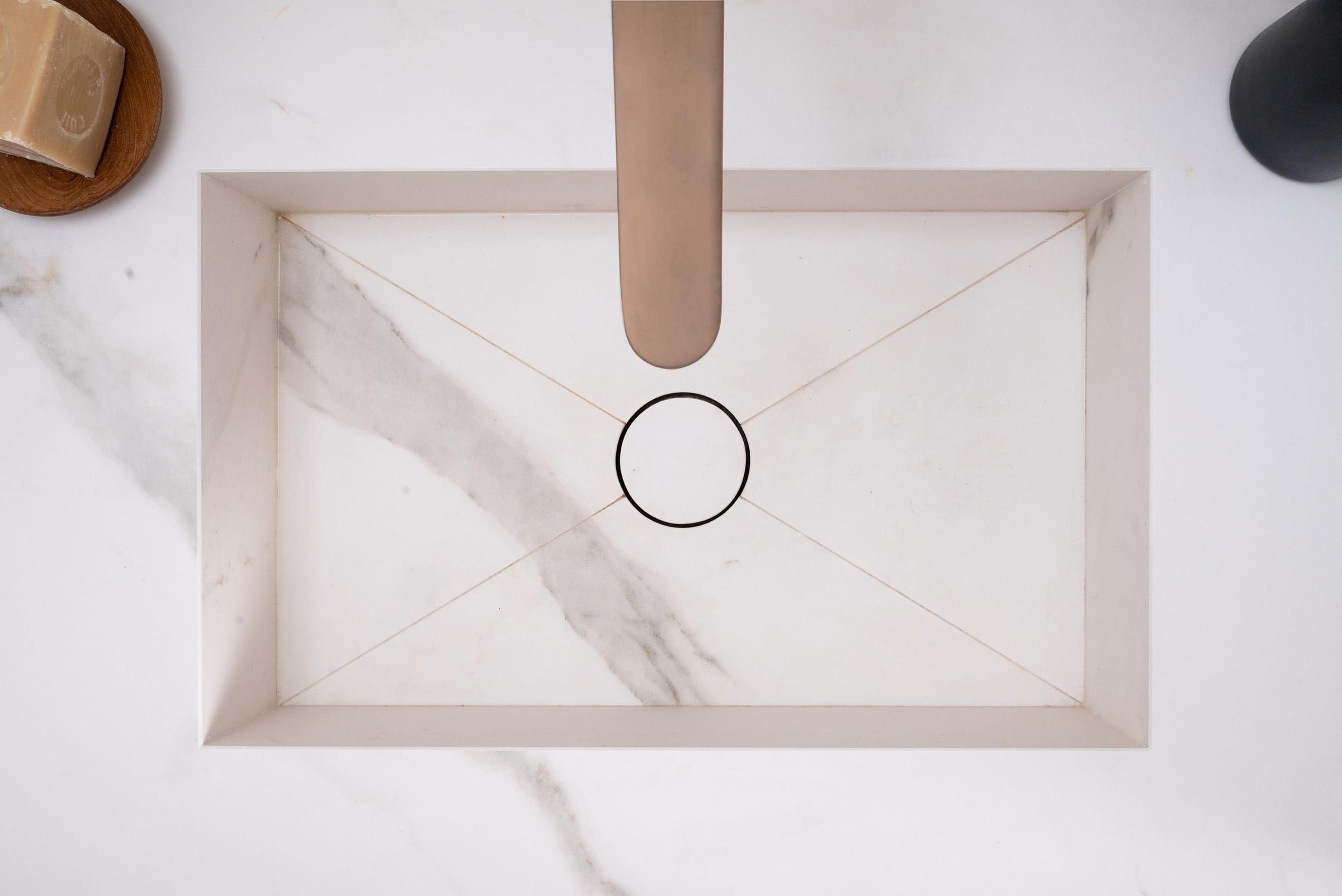 White marble basin with a copper tap, seen from above