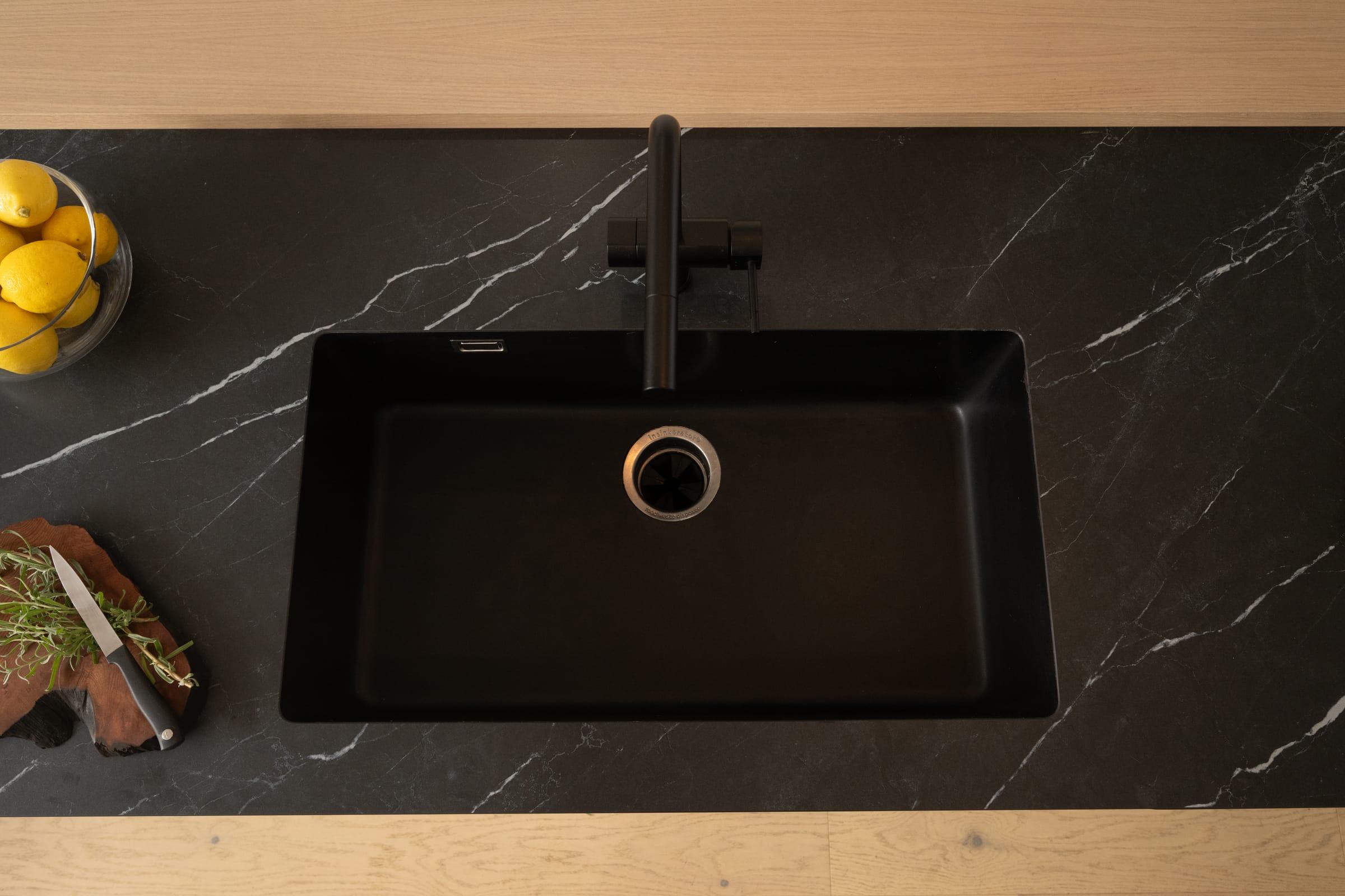 Black sink in a dark marble worktop