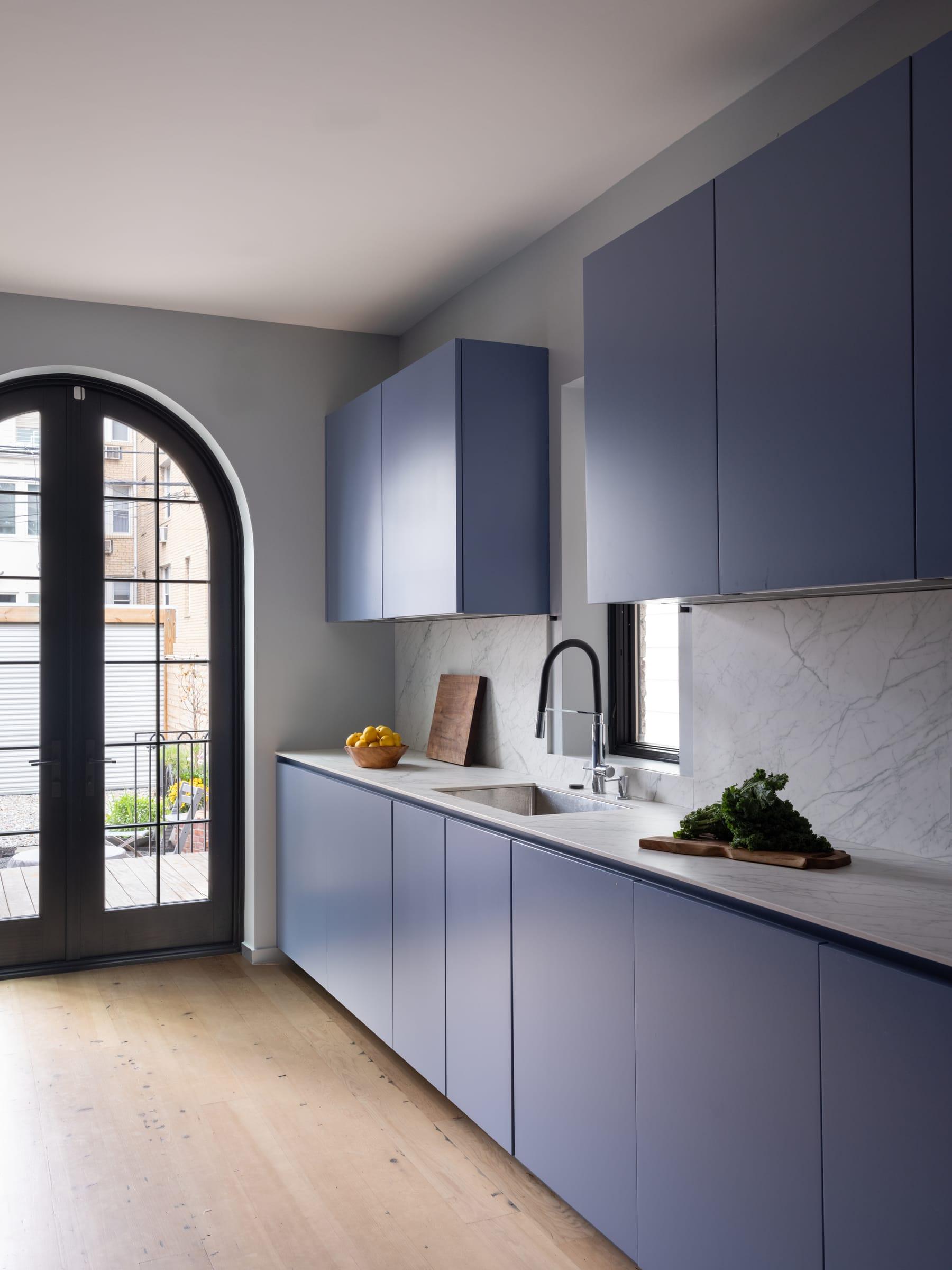 Blue kitchen run with a marble splashback and an arched door