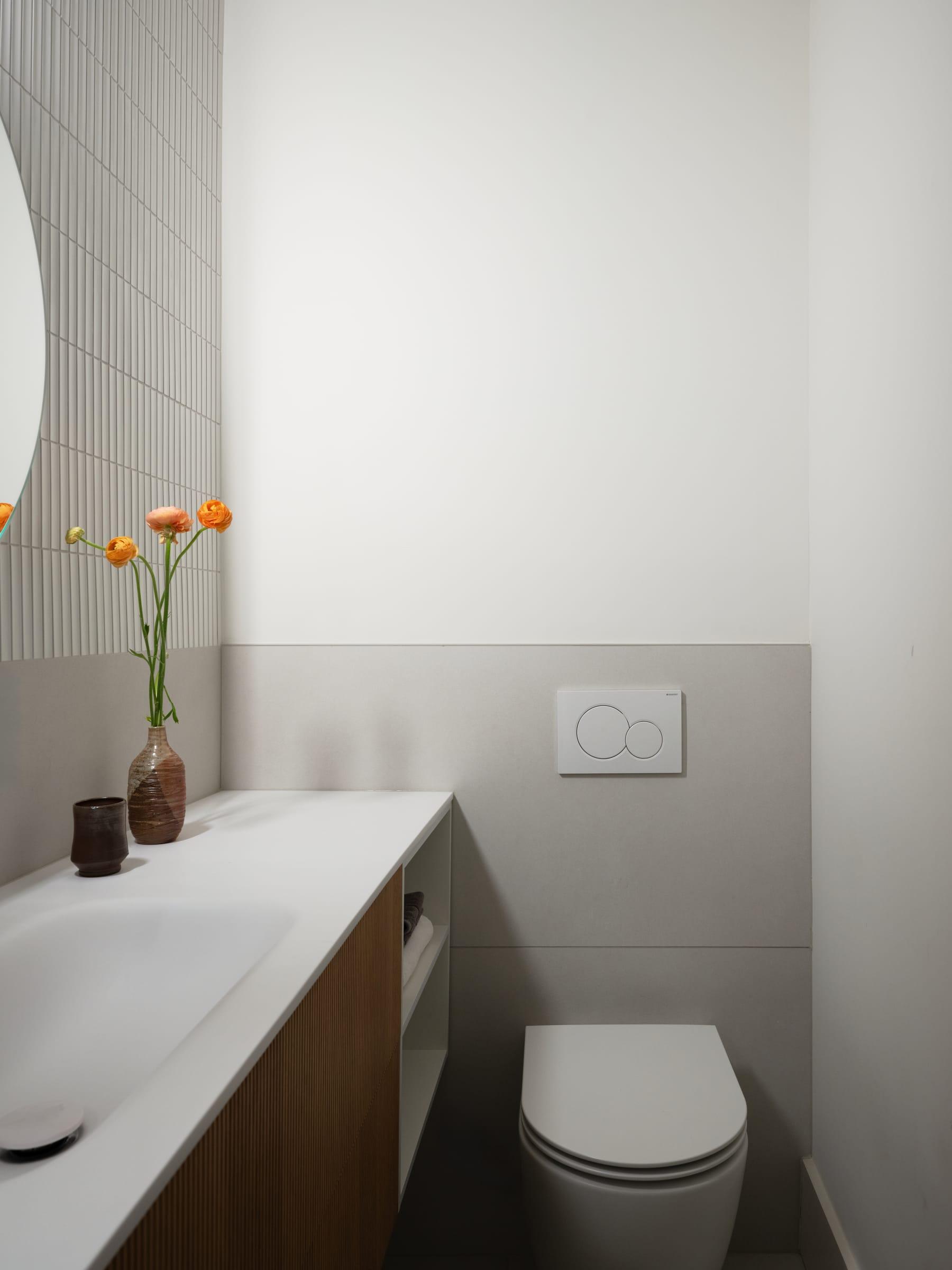 White washbasin top over a walnut cabinet with a vase of tulips