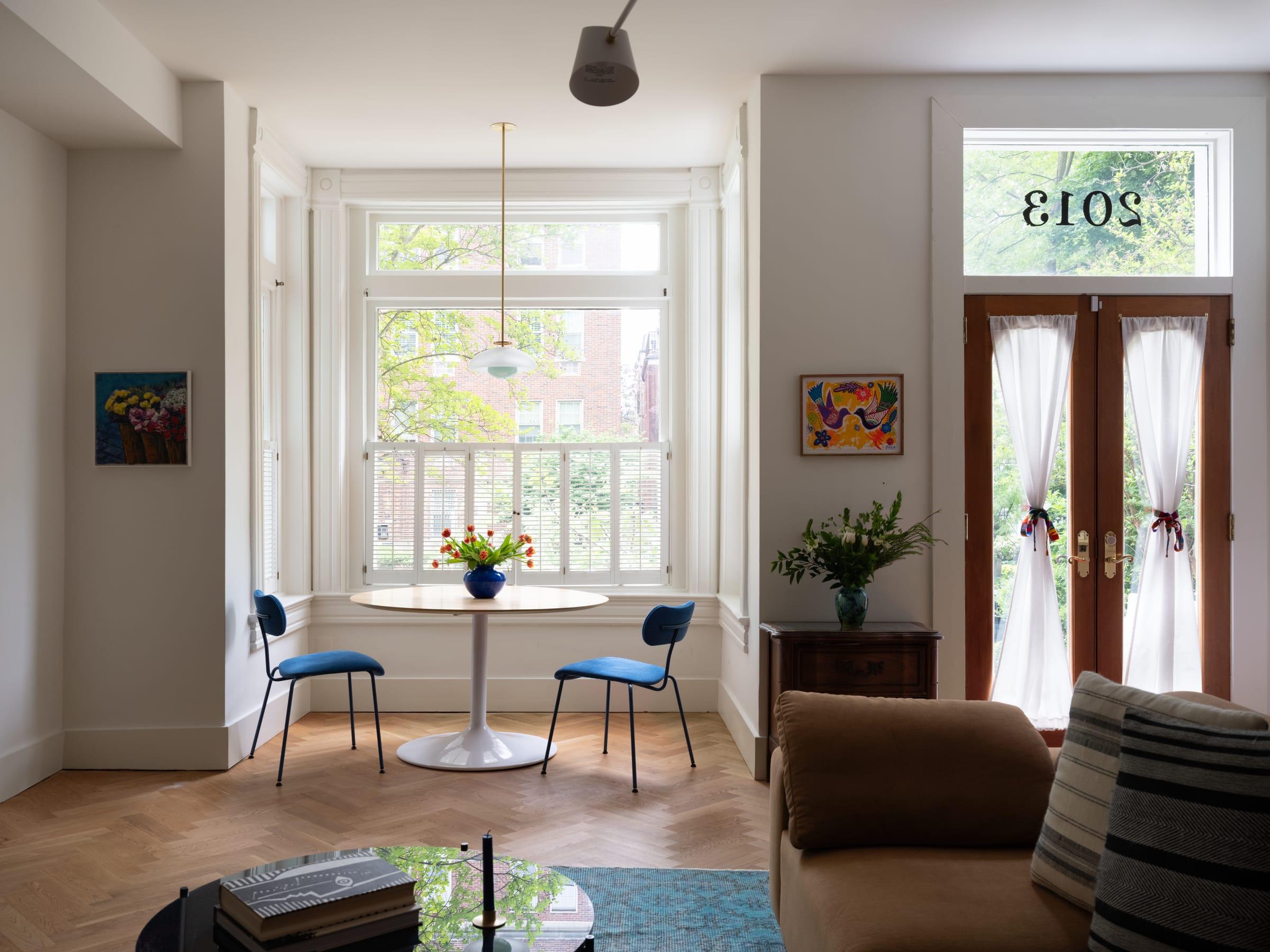 Bay window with a round table and blue chairs, seen from the sofa