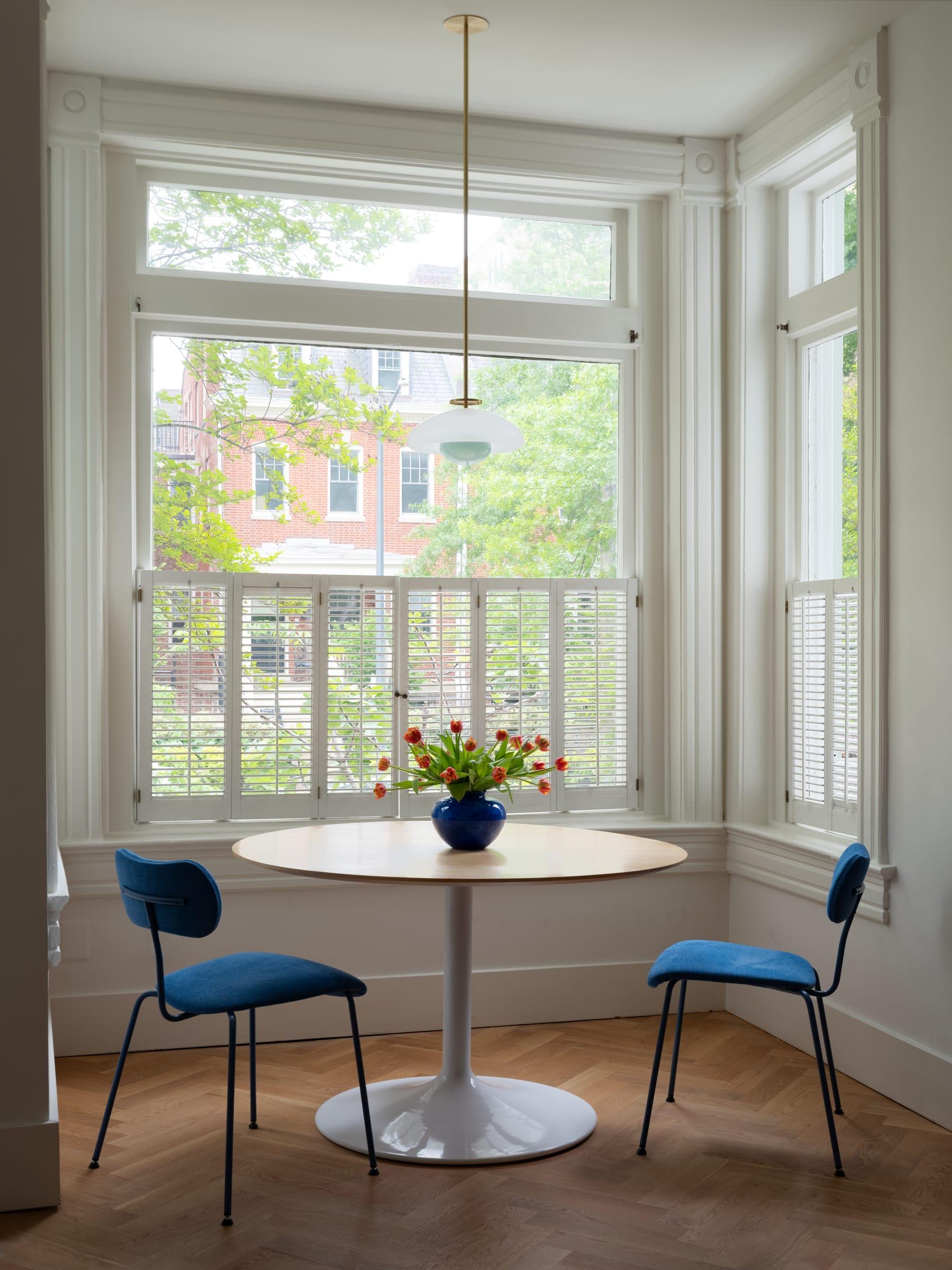 Round table with blue chairs in a bay window