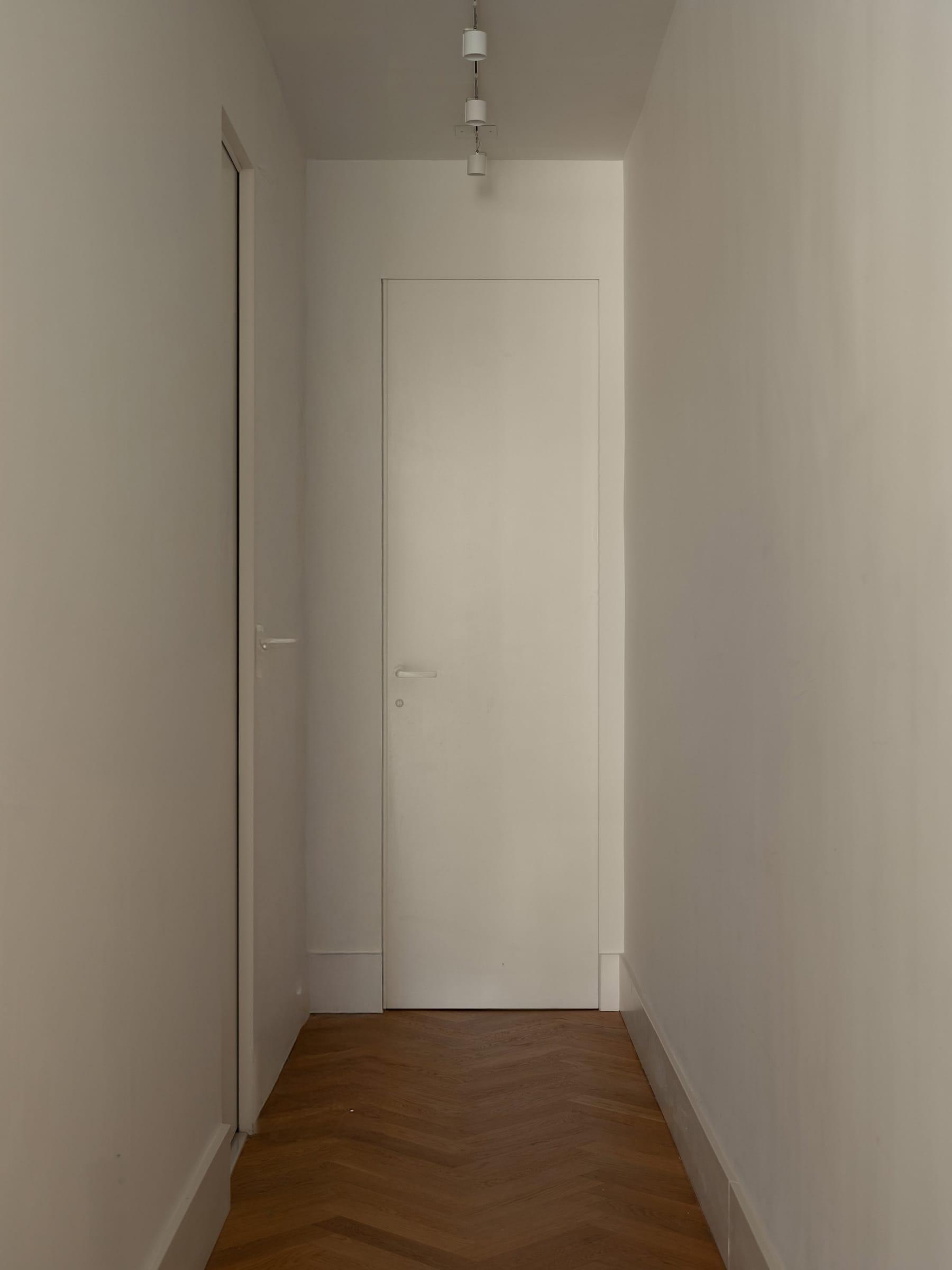White corridor with flush doors and a herringbone floor