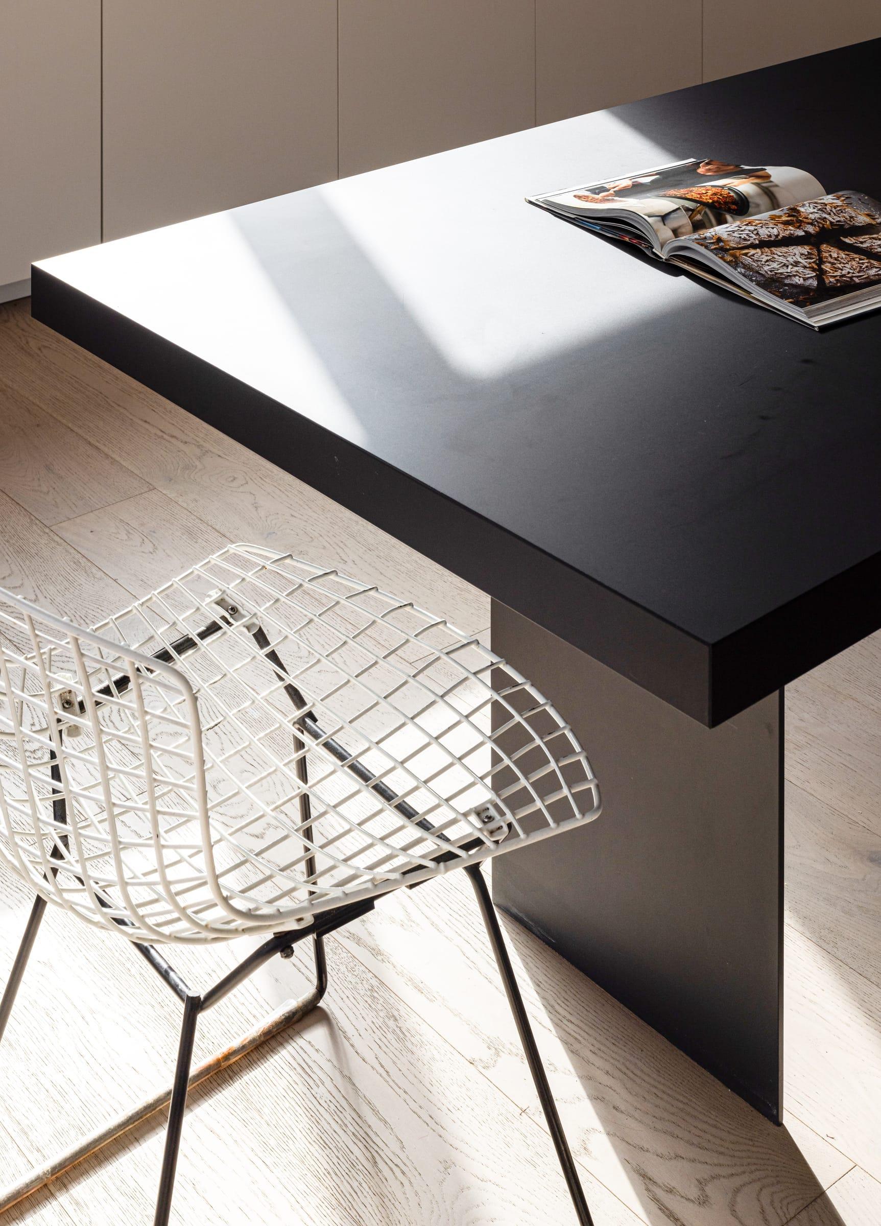 Corner of the dark grey island top with a wire chair