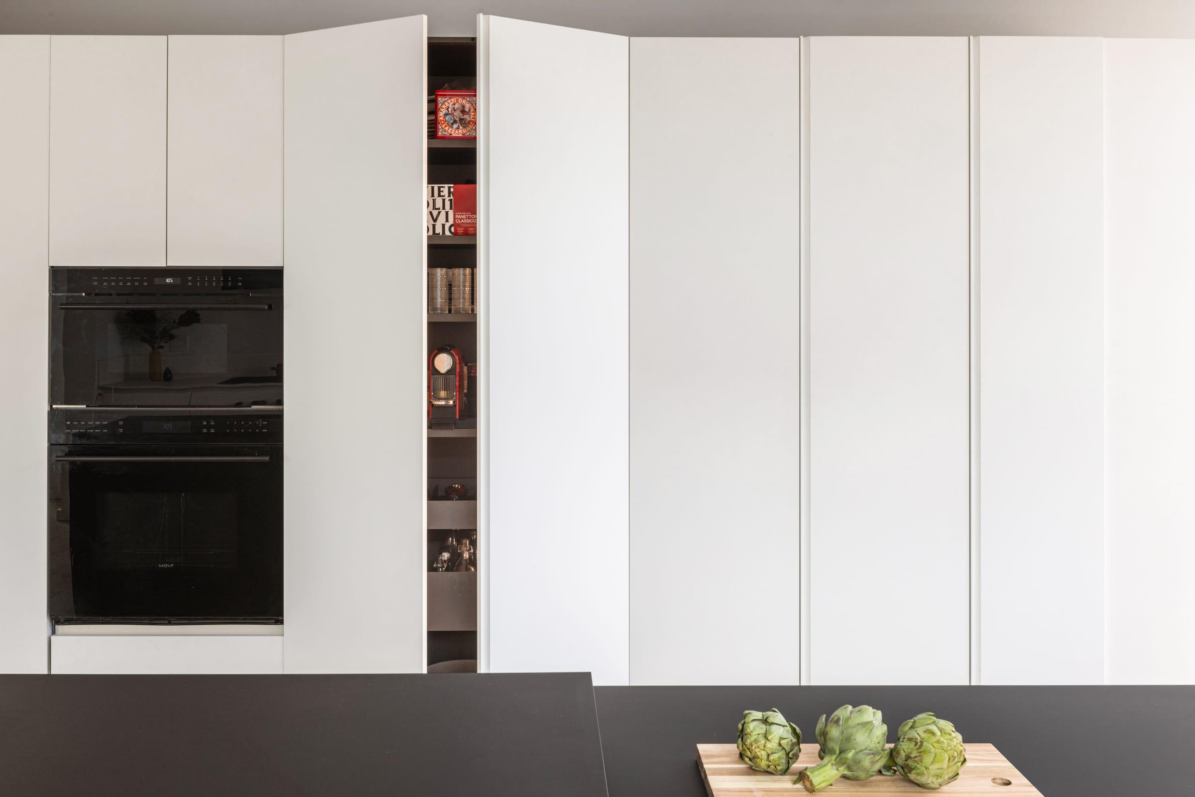 White tall units with a black oven and a lit open niche