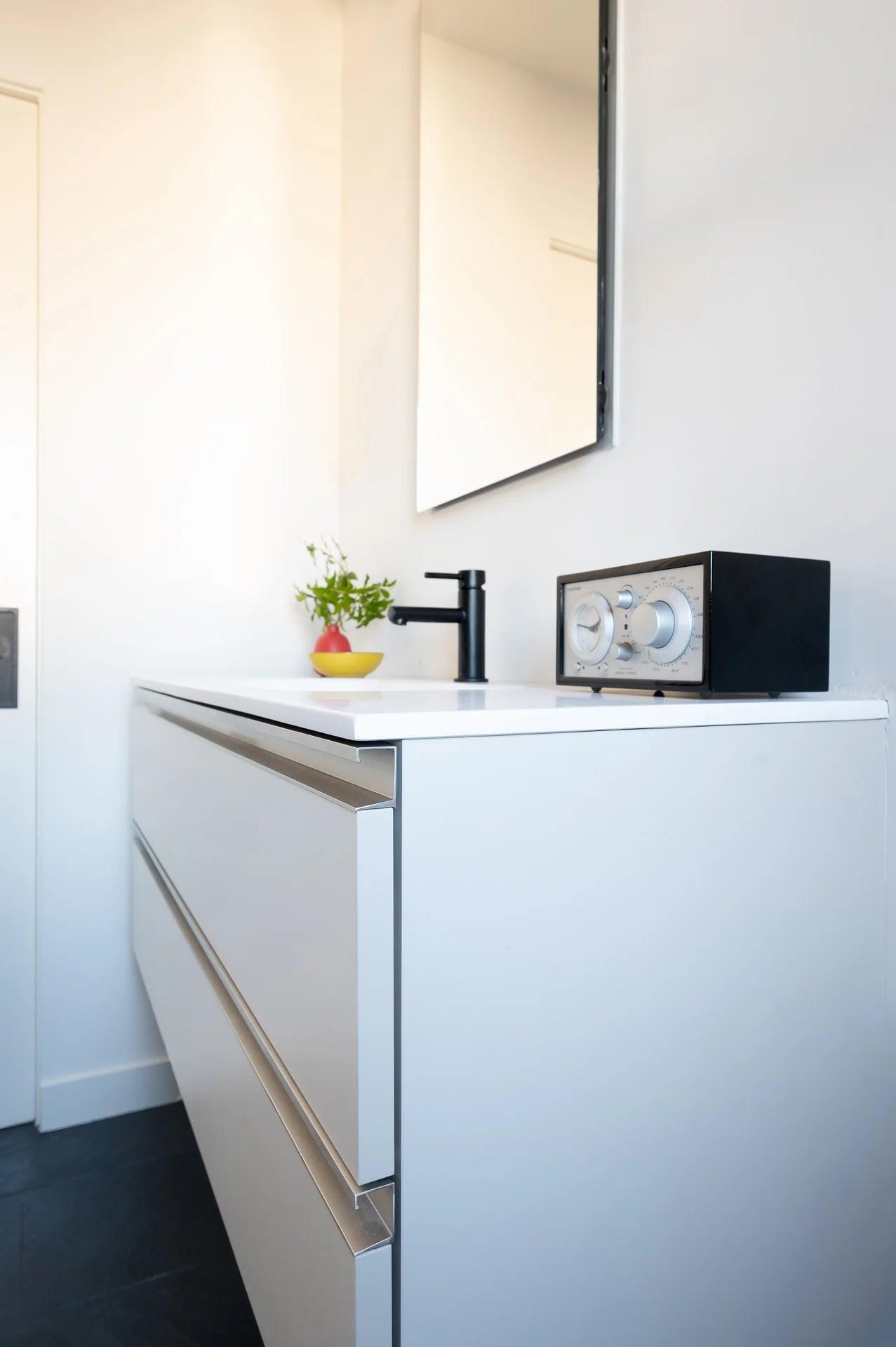 White vanity with a mirror and a wall lamp