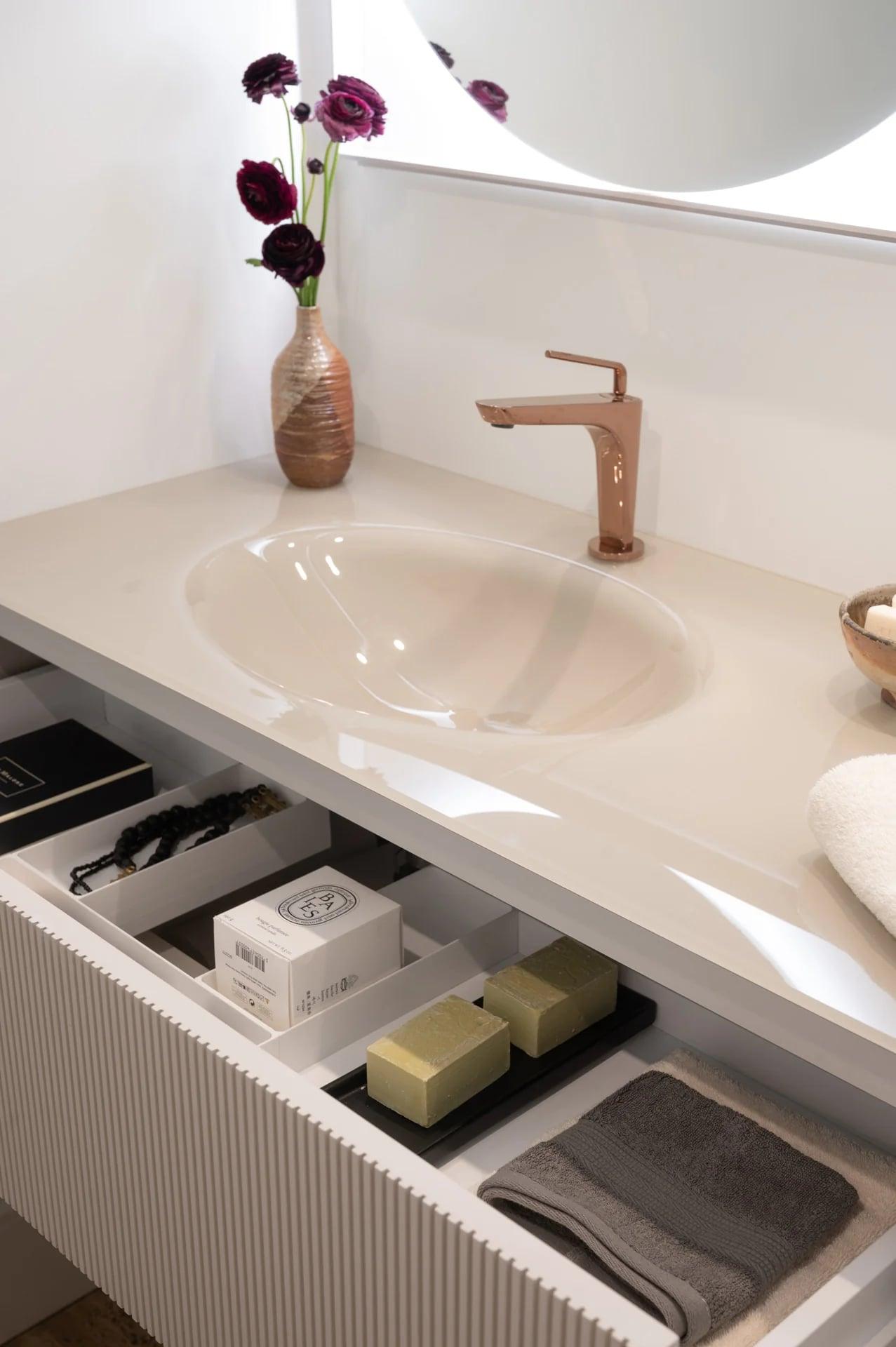 Drawer of the reeded vanity open with towels and toiletries