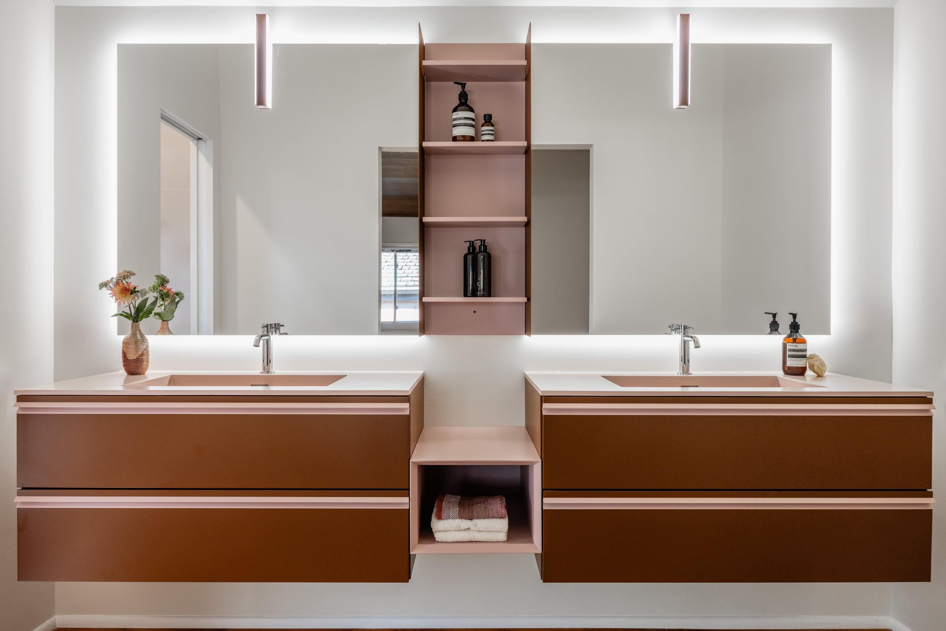 Walnut double vanity with two basins and open shelving between backlit mirrors