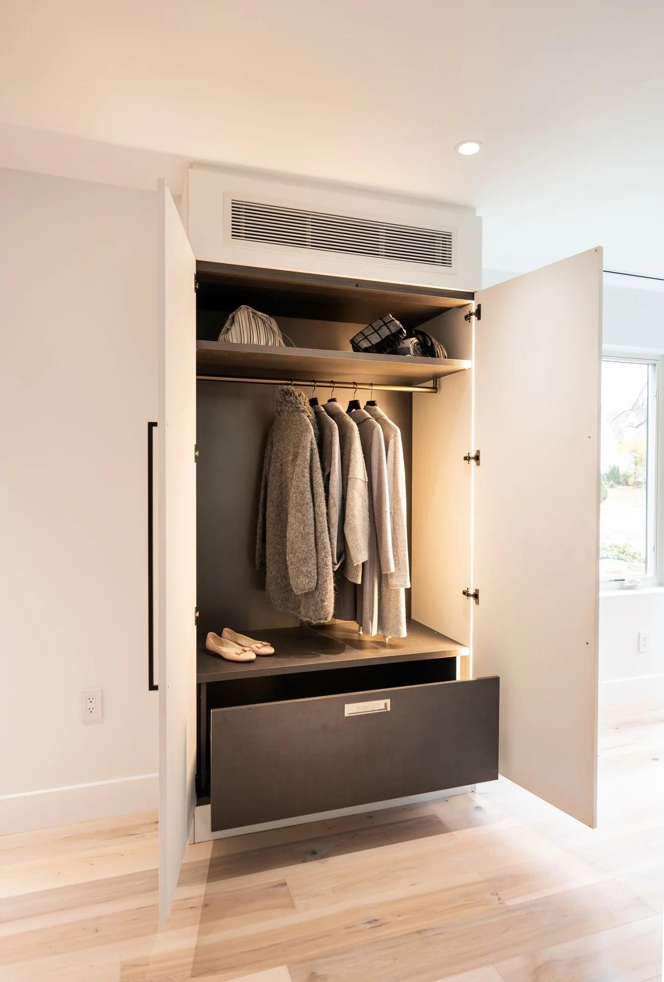 Wardrobe with doors open onto hanging clothes and a drawer
