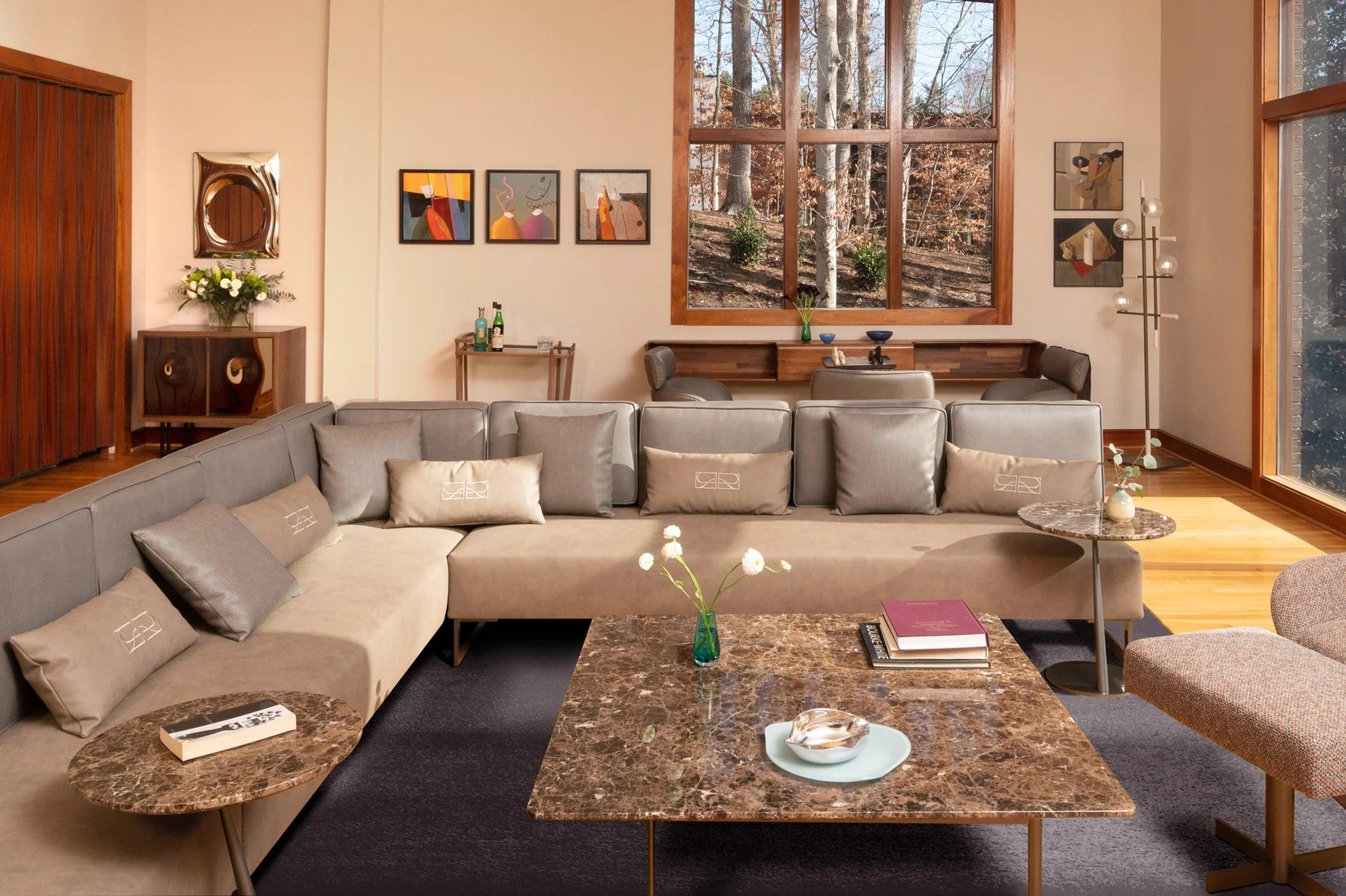 Living room with a taupe sectional sofa, marble tables and abstract paintings