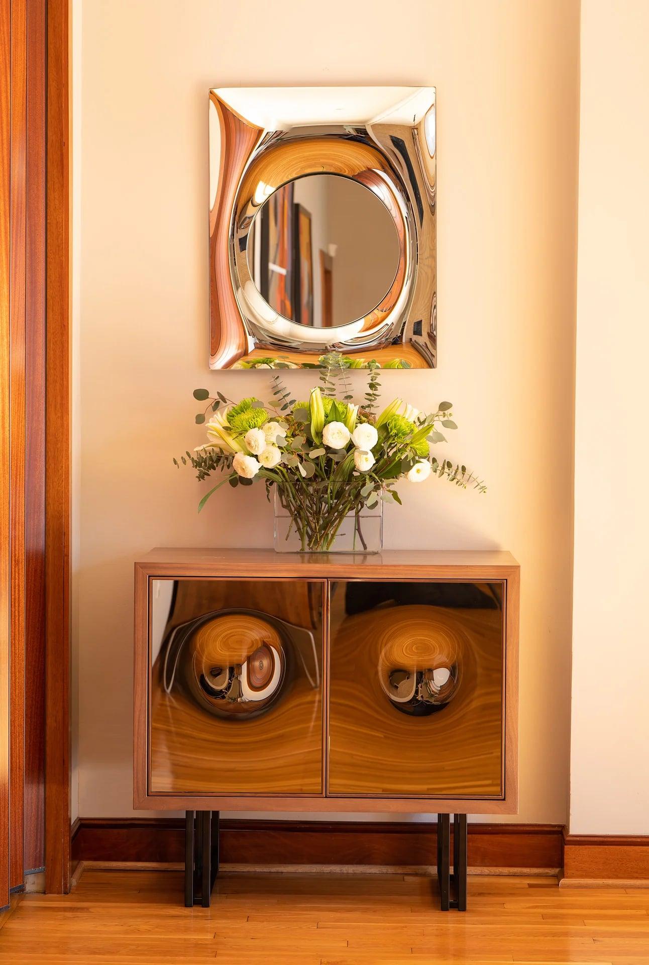 Backlit mirror on a brick wall with a small shelf