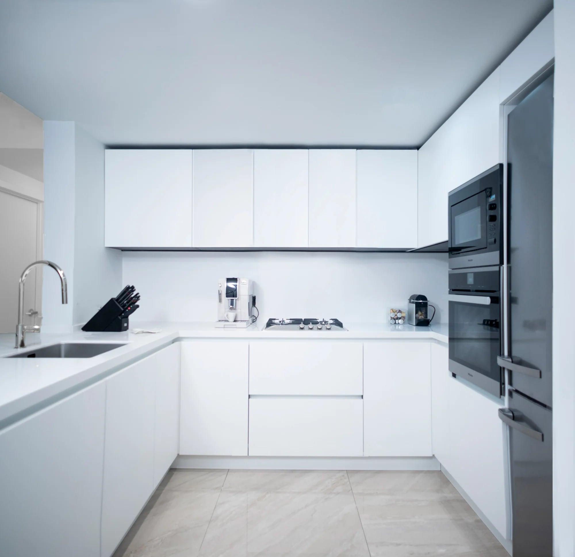 White kitchen with an island and Corian worktop, seen from the stairs