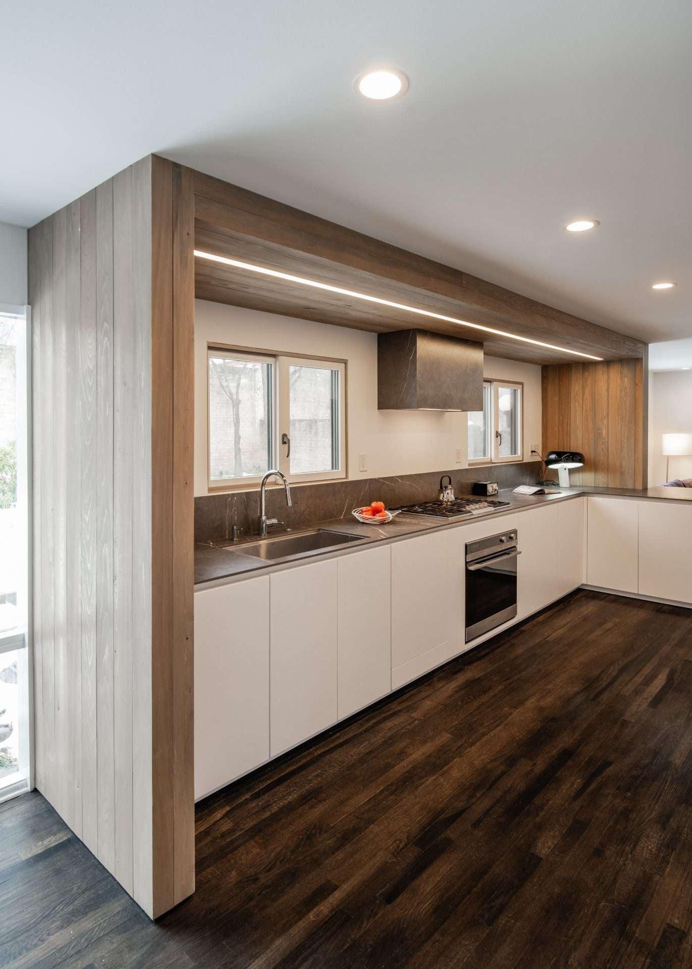 White run of cabinets under a wood-clad hood with a window