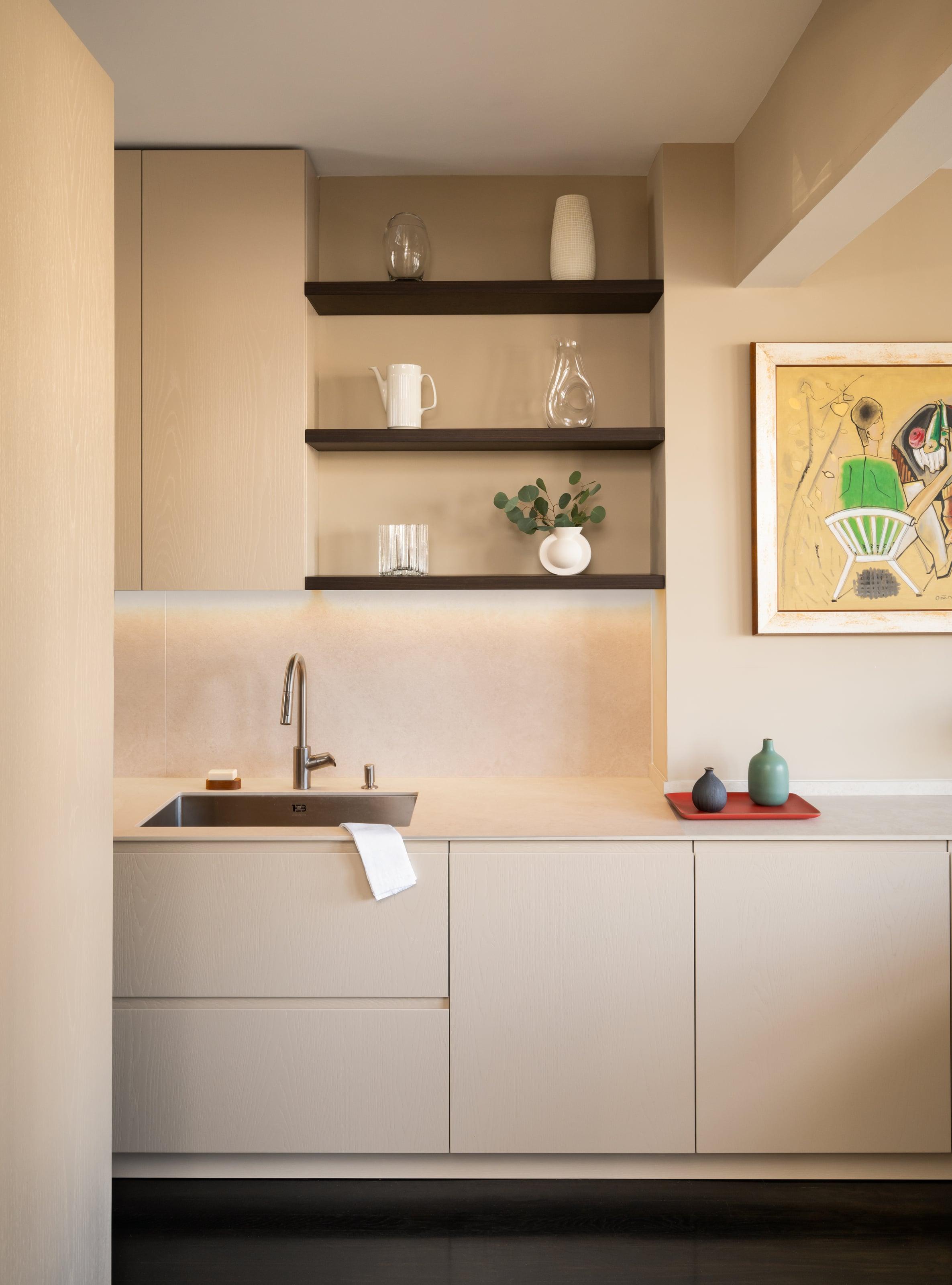 Grey painted wall units over oak base cabinets with a blue stool
