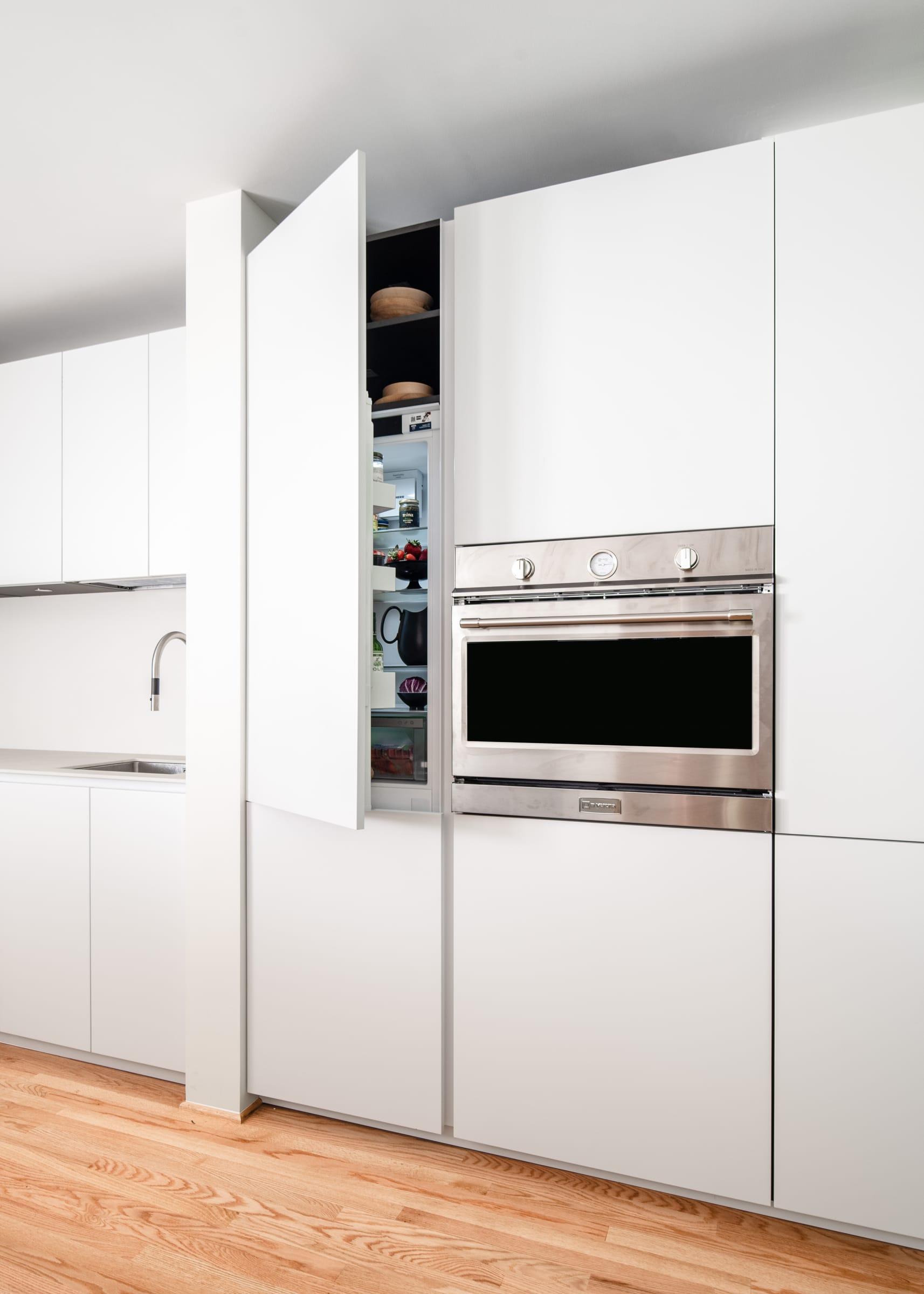 White tall units with an oven and an open larder door