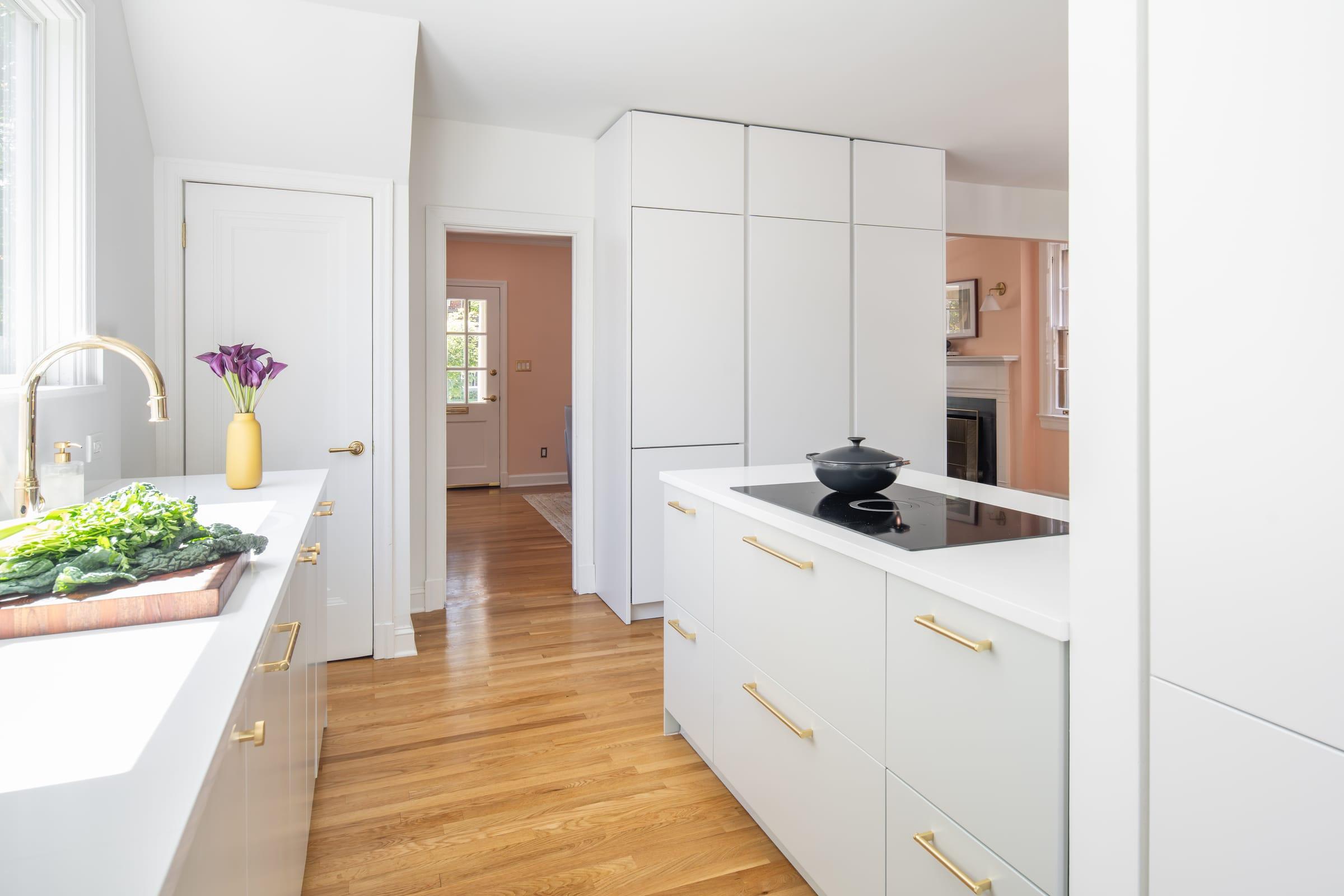 White kitchen with brass handles, an island hob and a vase of tulips