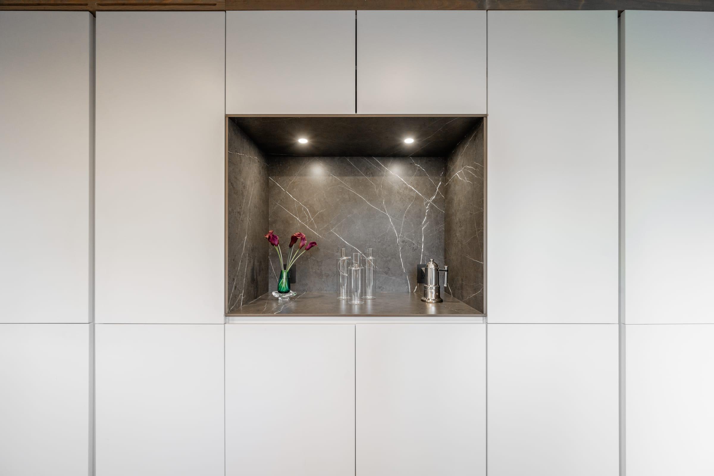 White tall units around a lit marble niche