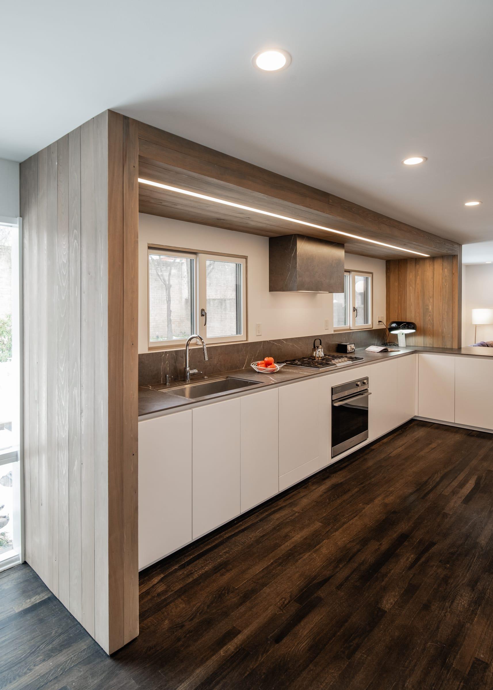 Wood-clad wall beside a white kitchen run