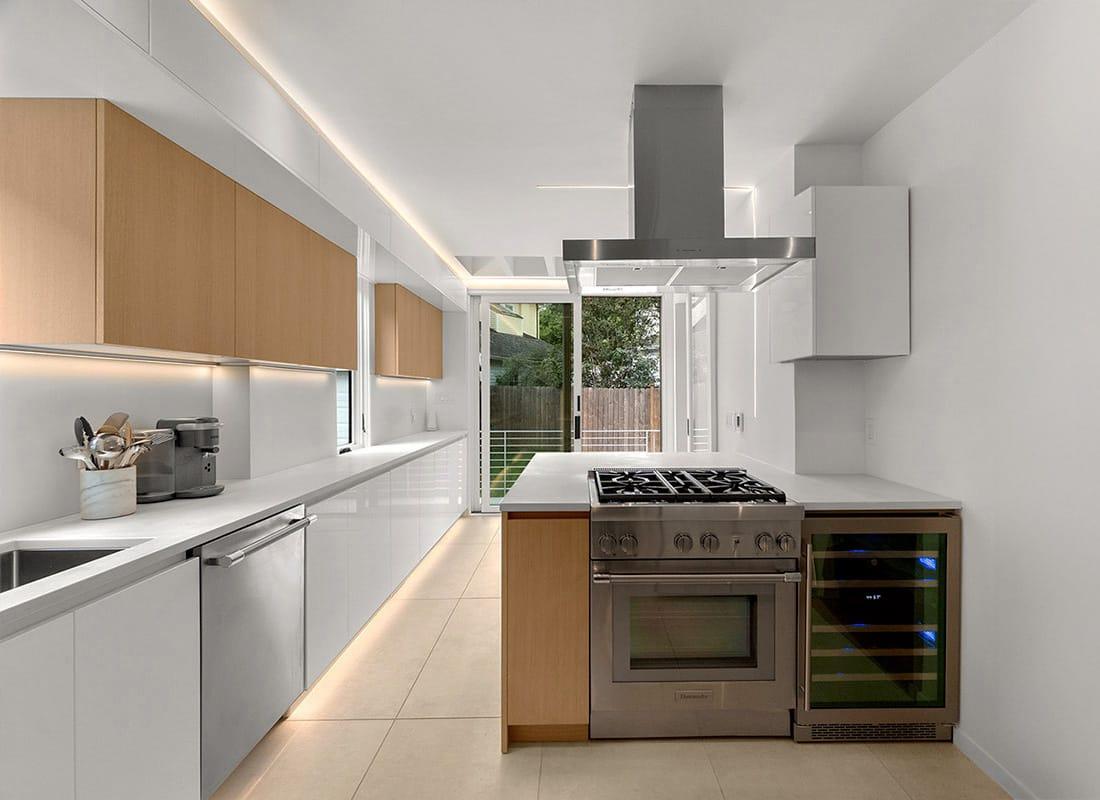 Galley kitchen in white and oak with a range and a steel hood, a garden door at the end