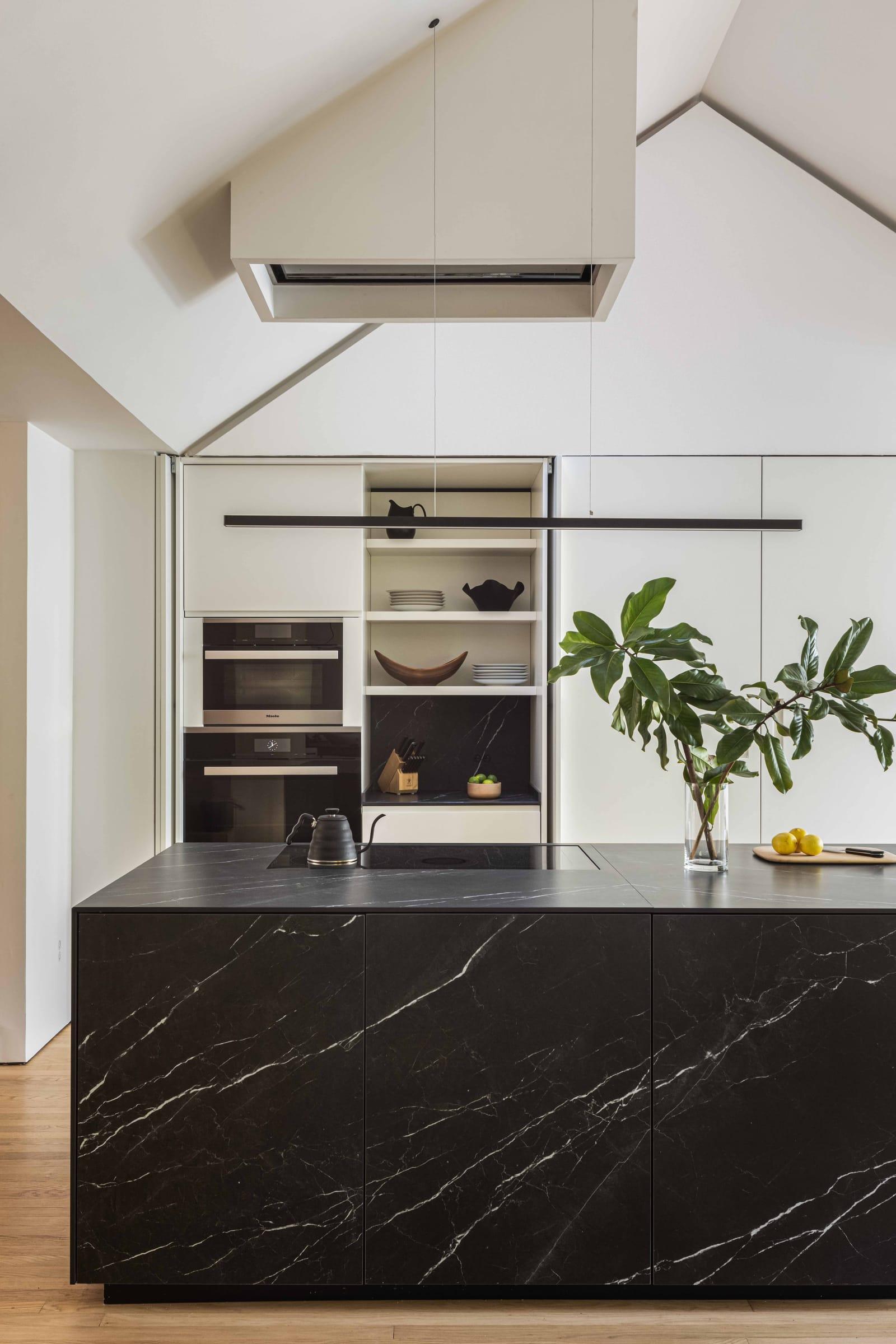 Black marble island before a wall of white units and a lit niche