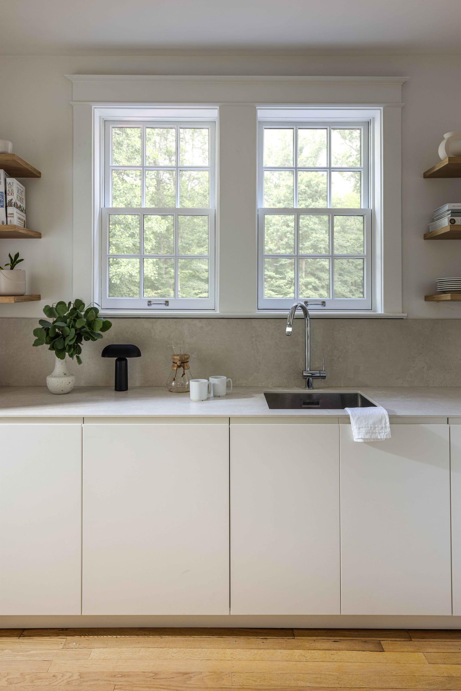 White kitchen with open shelves either side of two windows