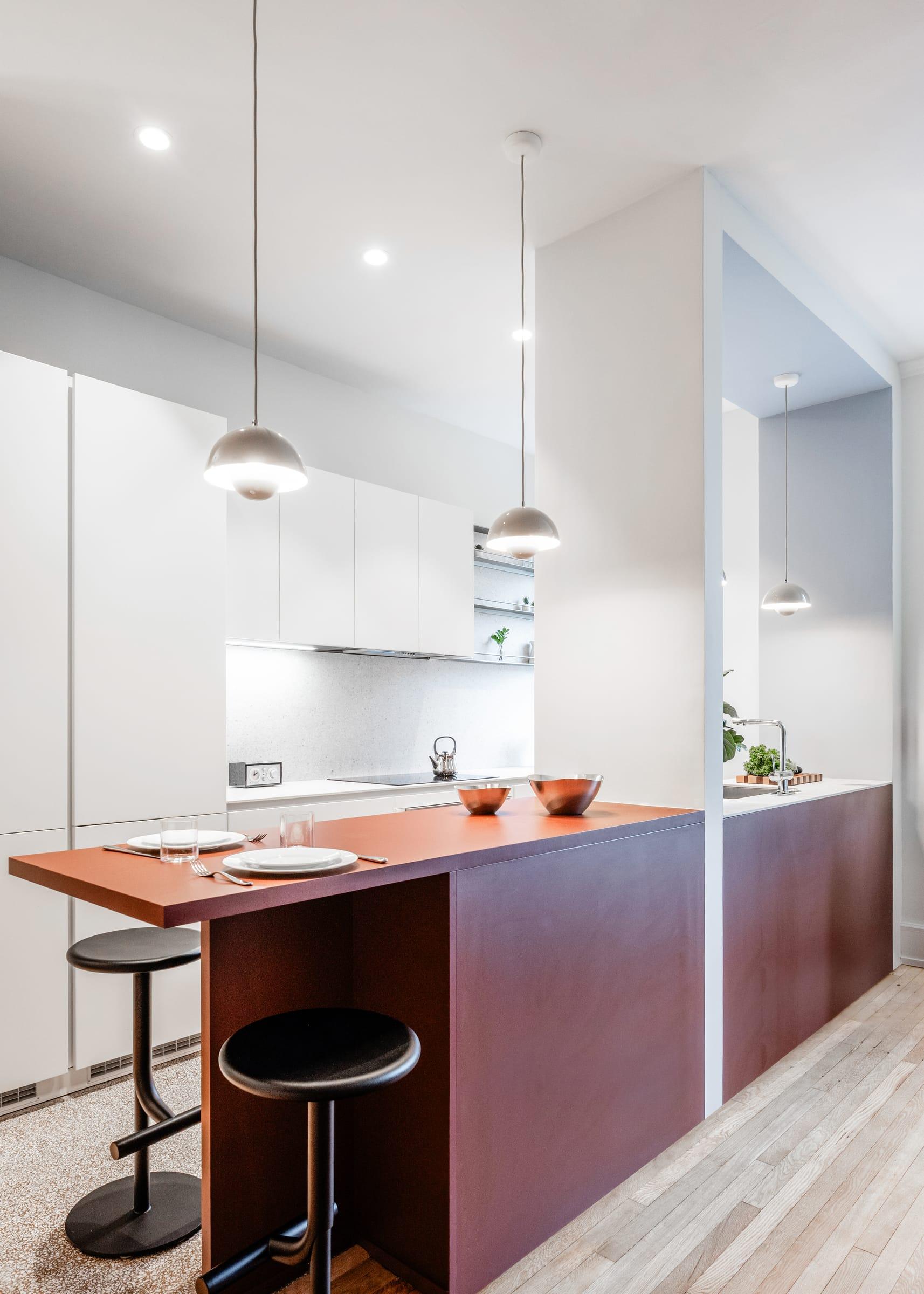 Burgundy island with black stools under glass pendants
