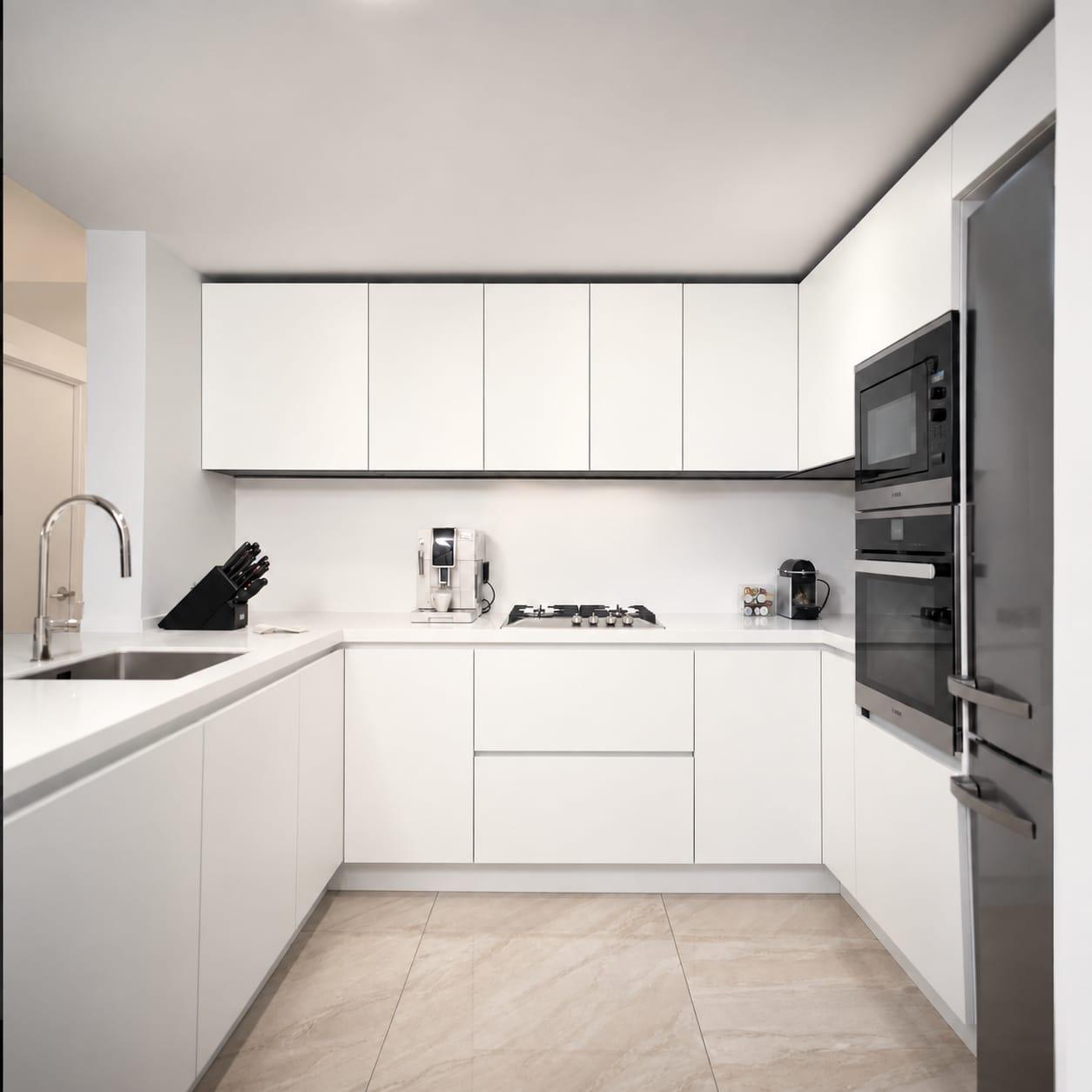 White U-shaped kitchen with tall dark ovens