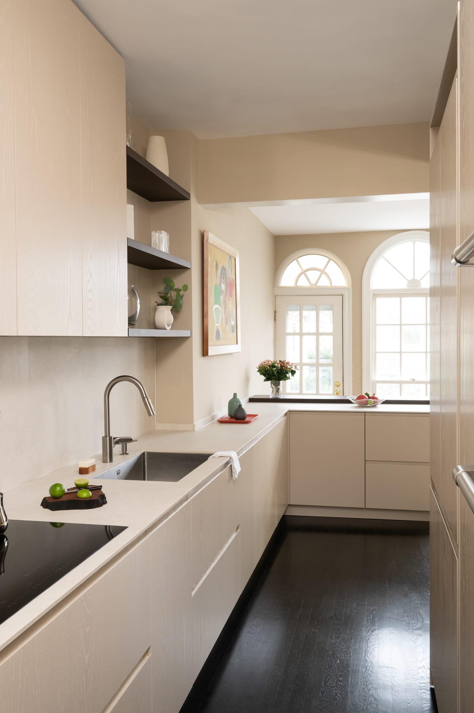 Pale kitchen run toward arched windows