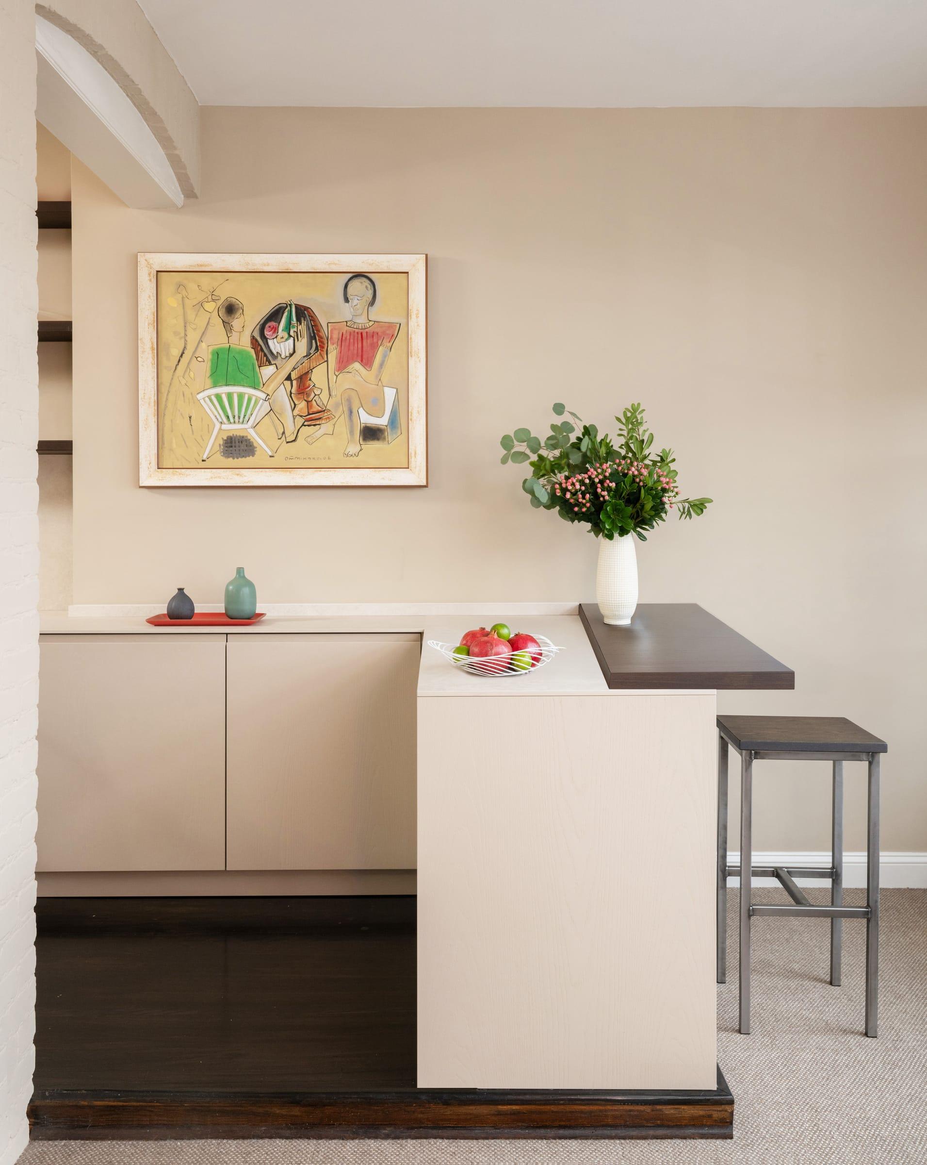 Pale kitchen with a dark peninsula top and a stool
