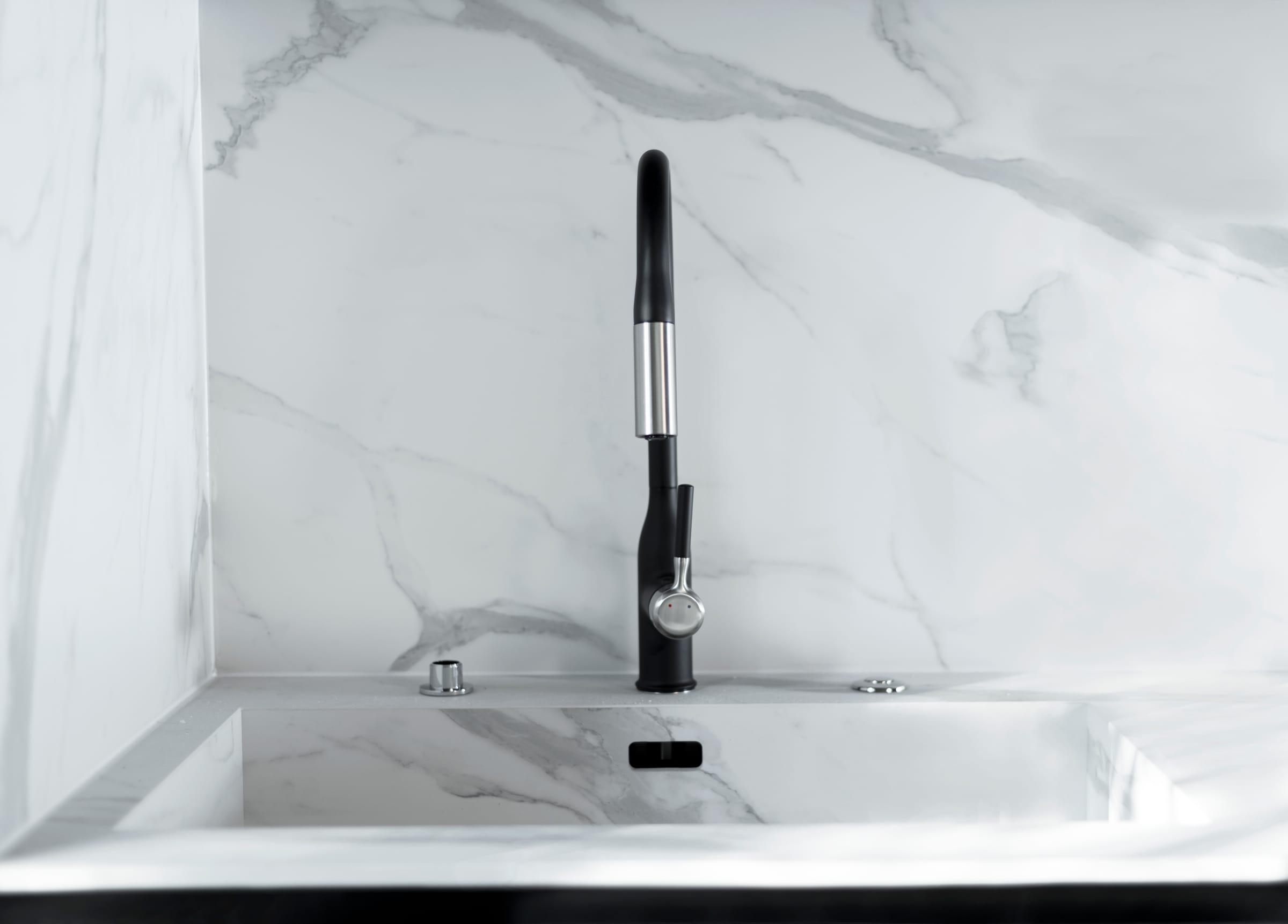Black tap over a marble sink cut into the worktop