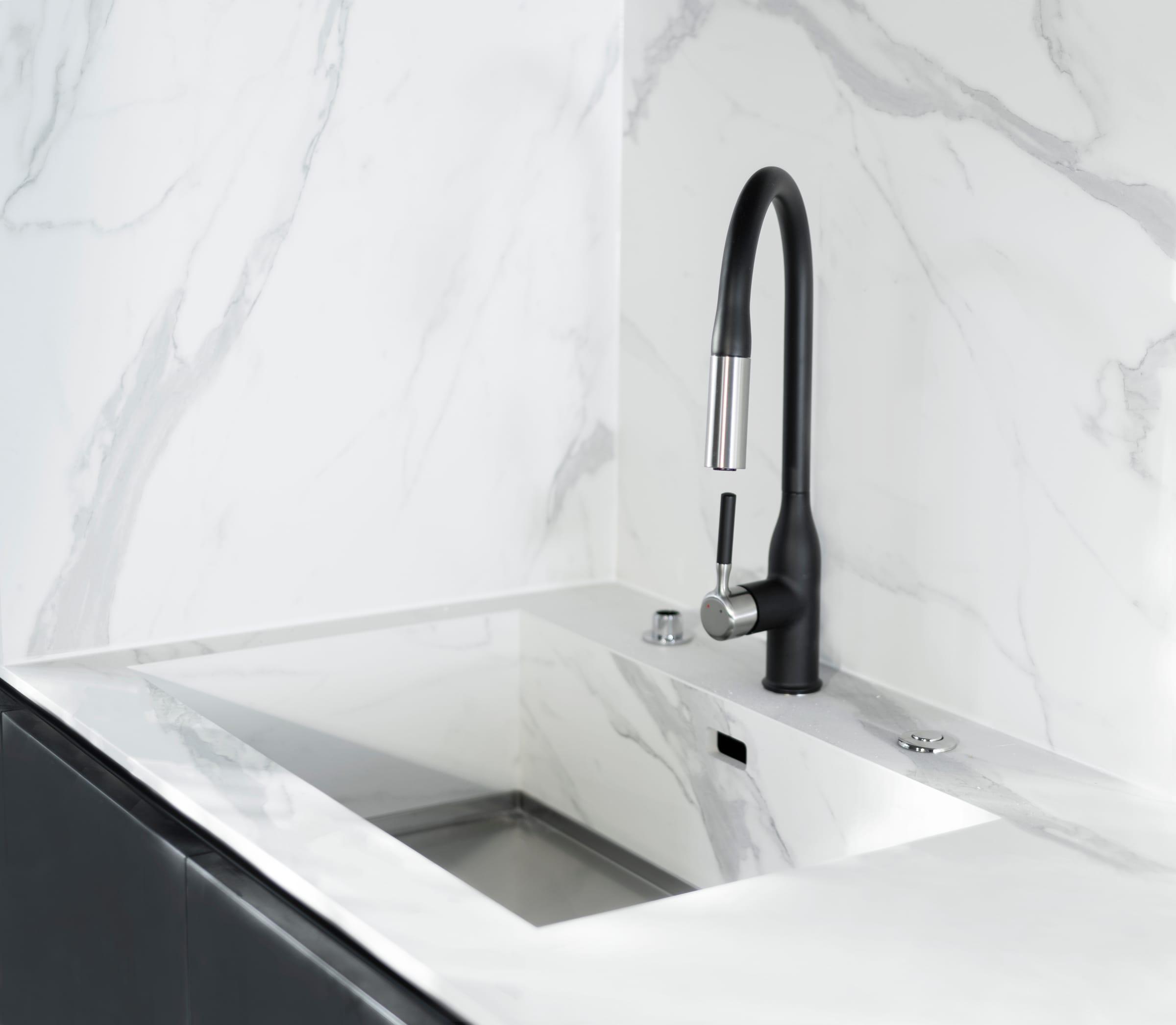 Marble sink with a black pull-out tap in the corner of the worktop