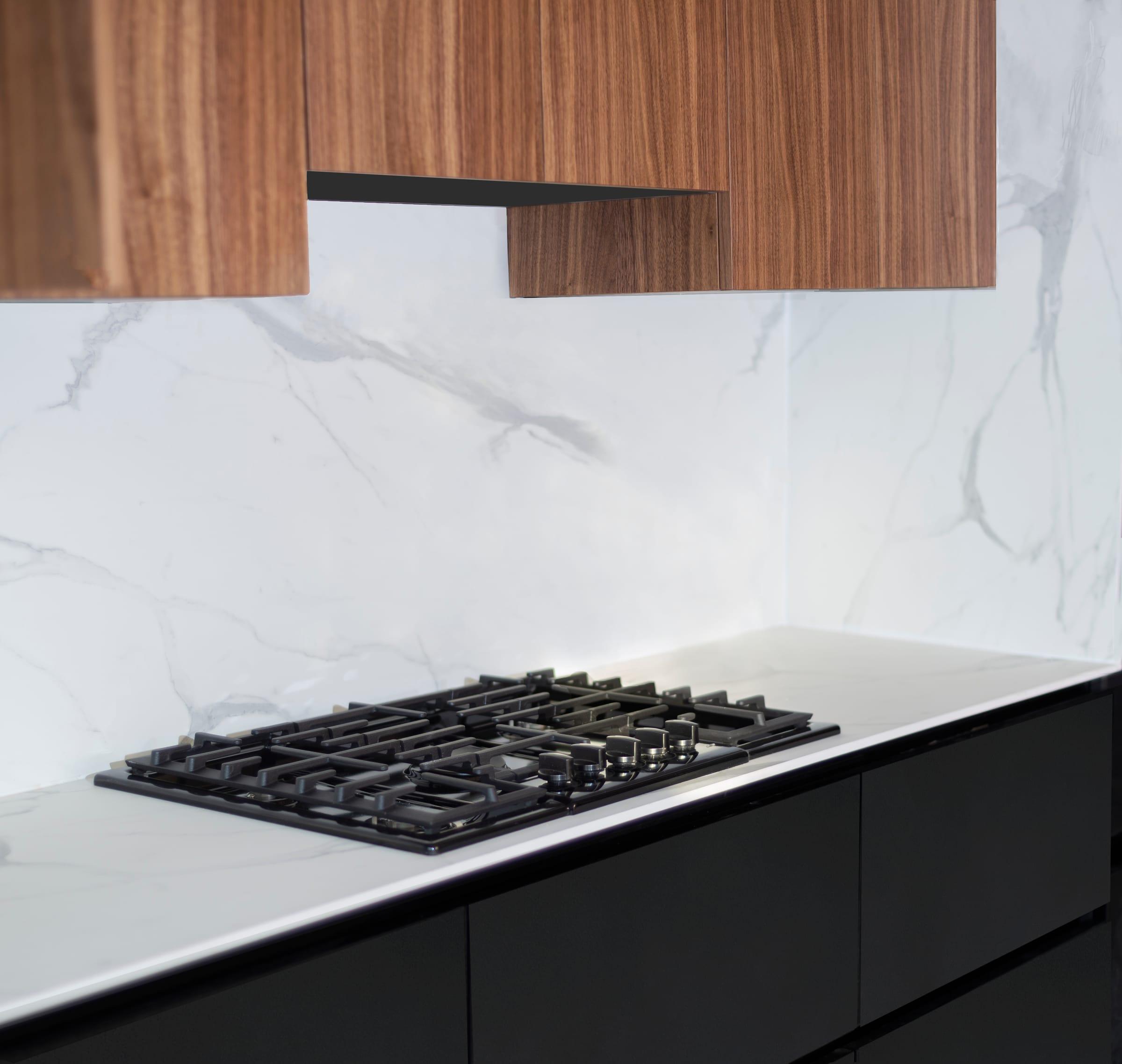 Gas hob on a white worktop under walnut wall units