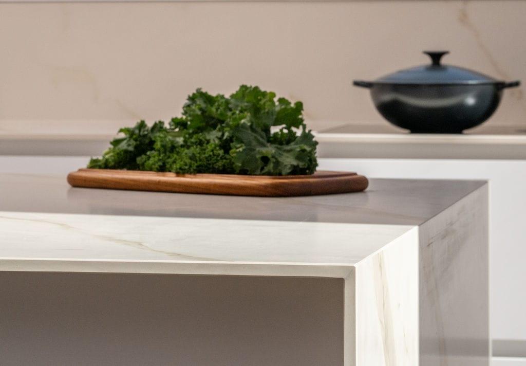 Marble worktop with greens on a board and a black pot