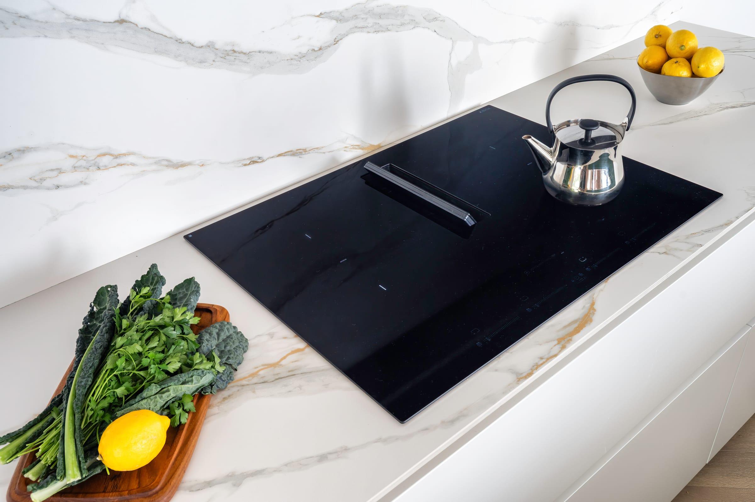 Black induction hob in a white marble worktop