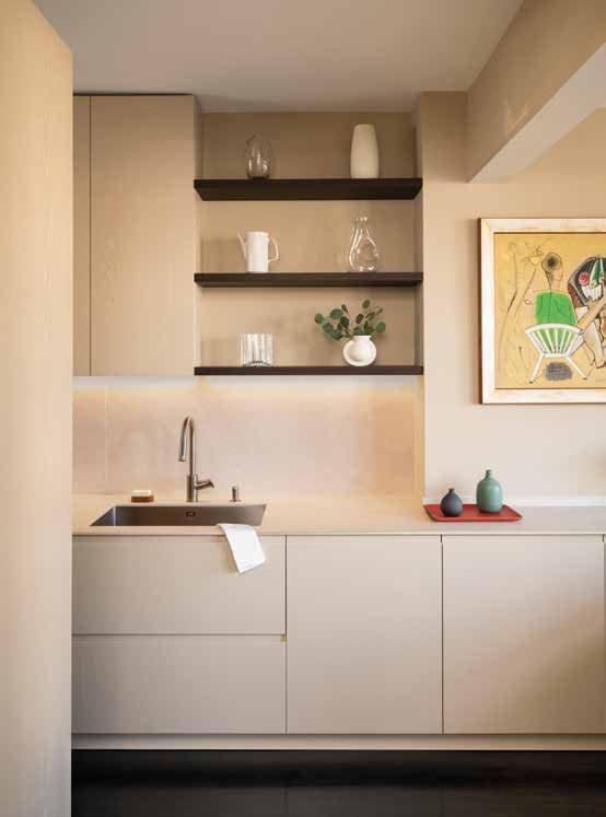 Pale kitchen with open dark shelves and a painting on the wall