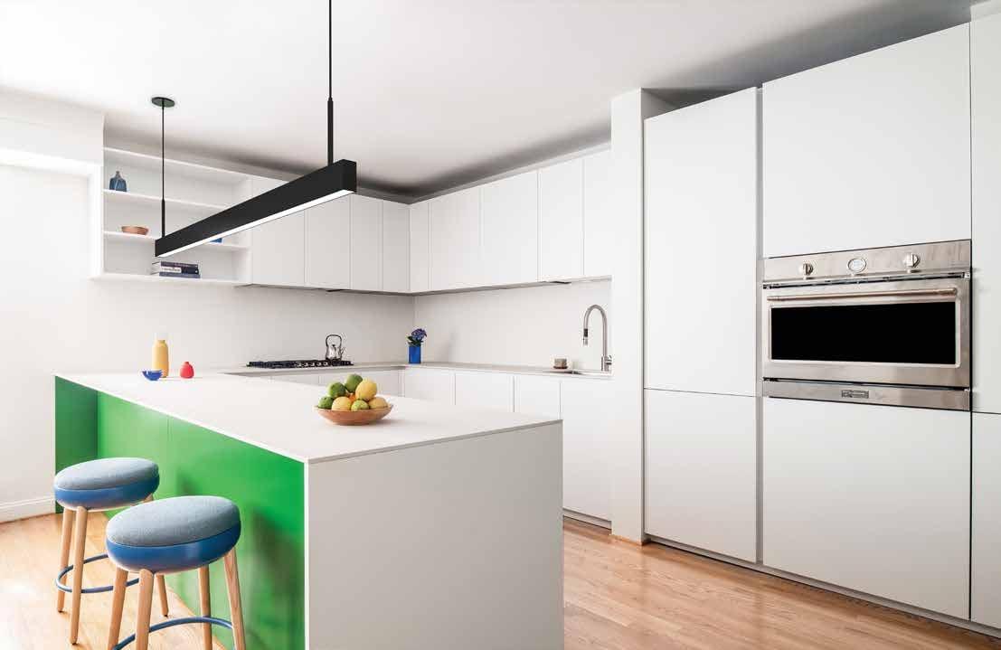 White kitchen with a green island, blue stools and a black pendant