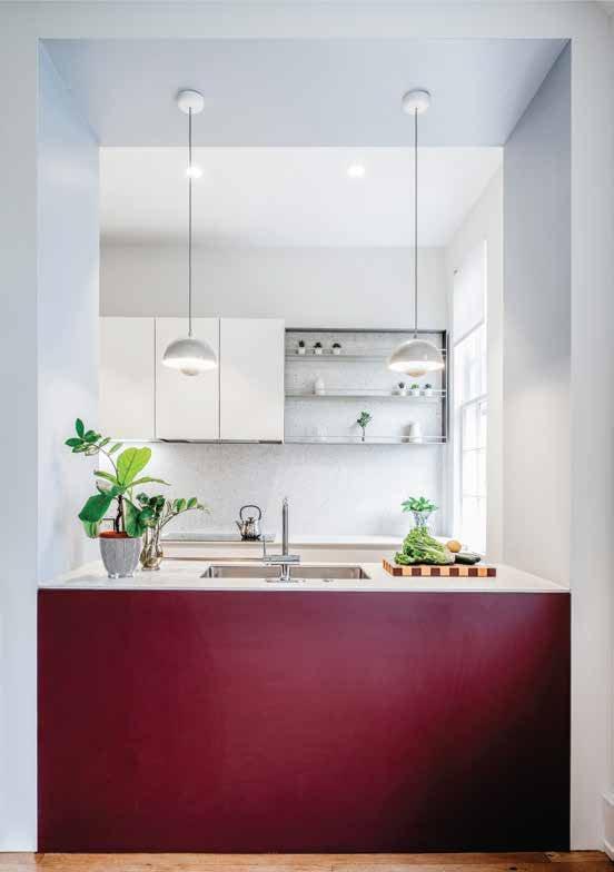 Burgundy island under glass pendants in a white kitchen