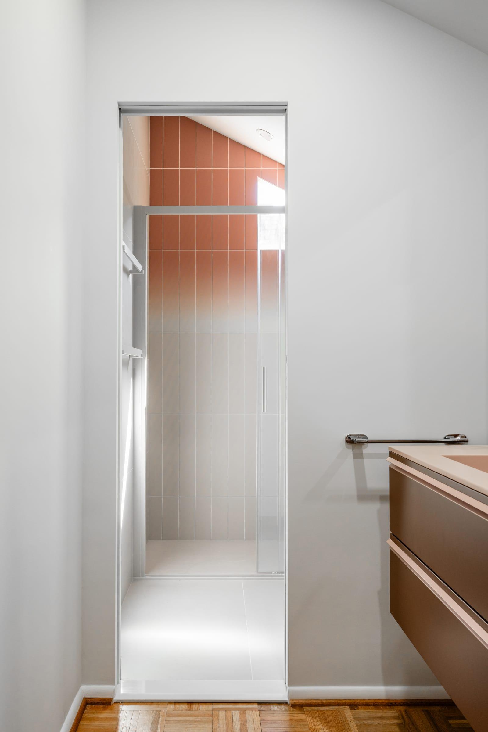 Walnut vanity beside a door onto a terracotta shower