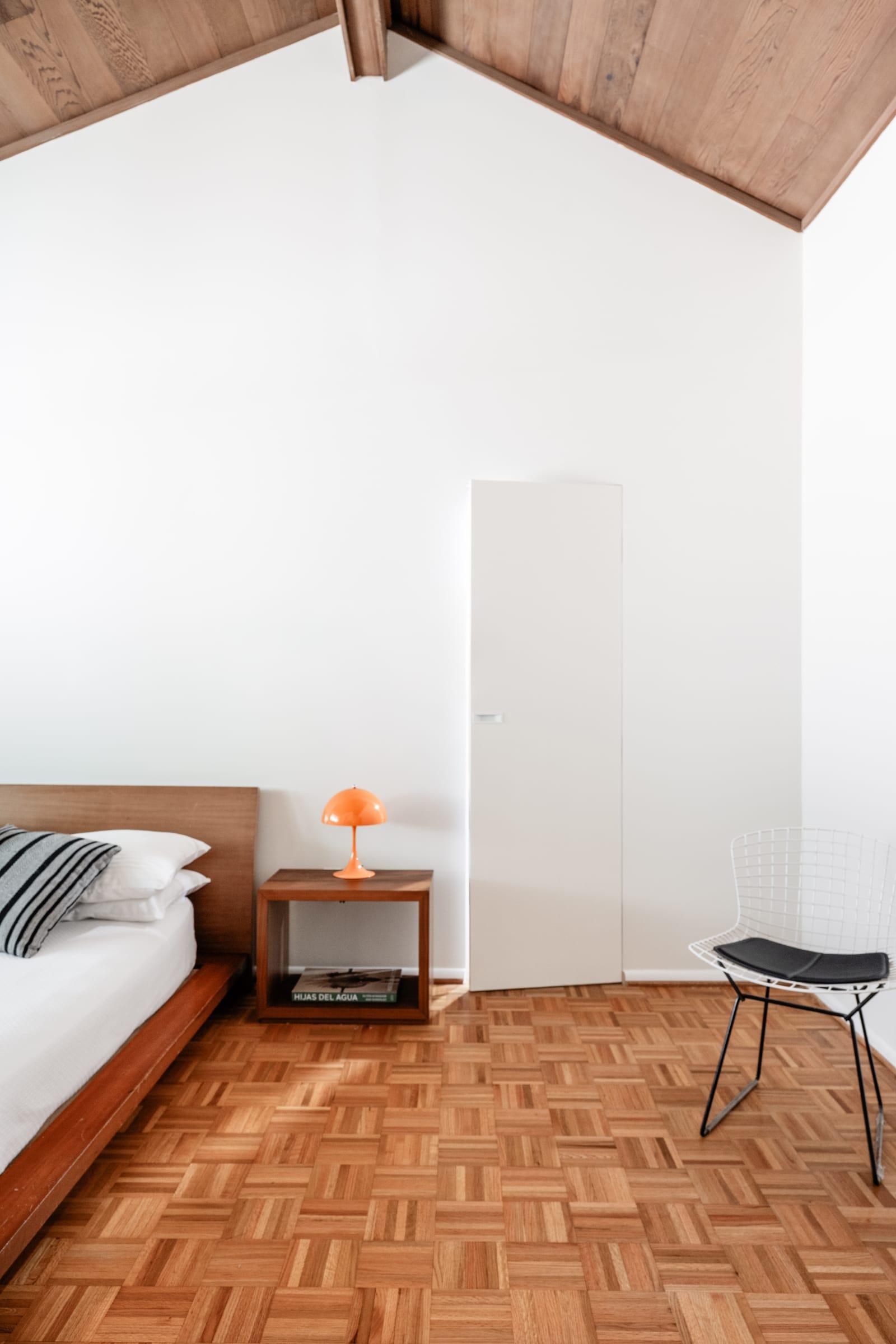 Bedroom under a wood ceiling with a walnut bedside table
