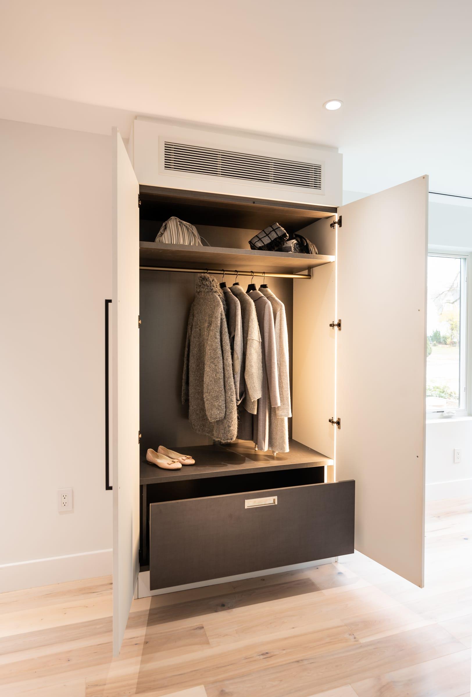 White wardrobe half open onto jackets and a dark drawer