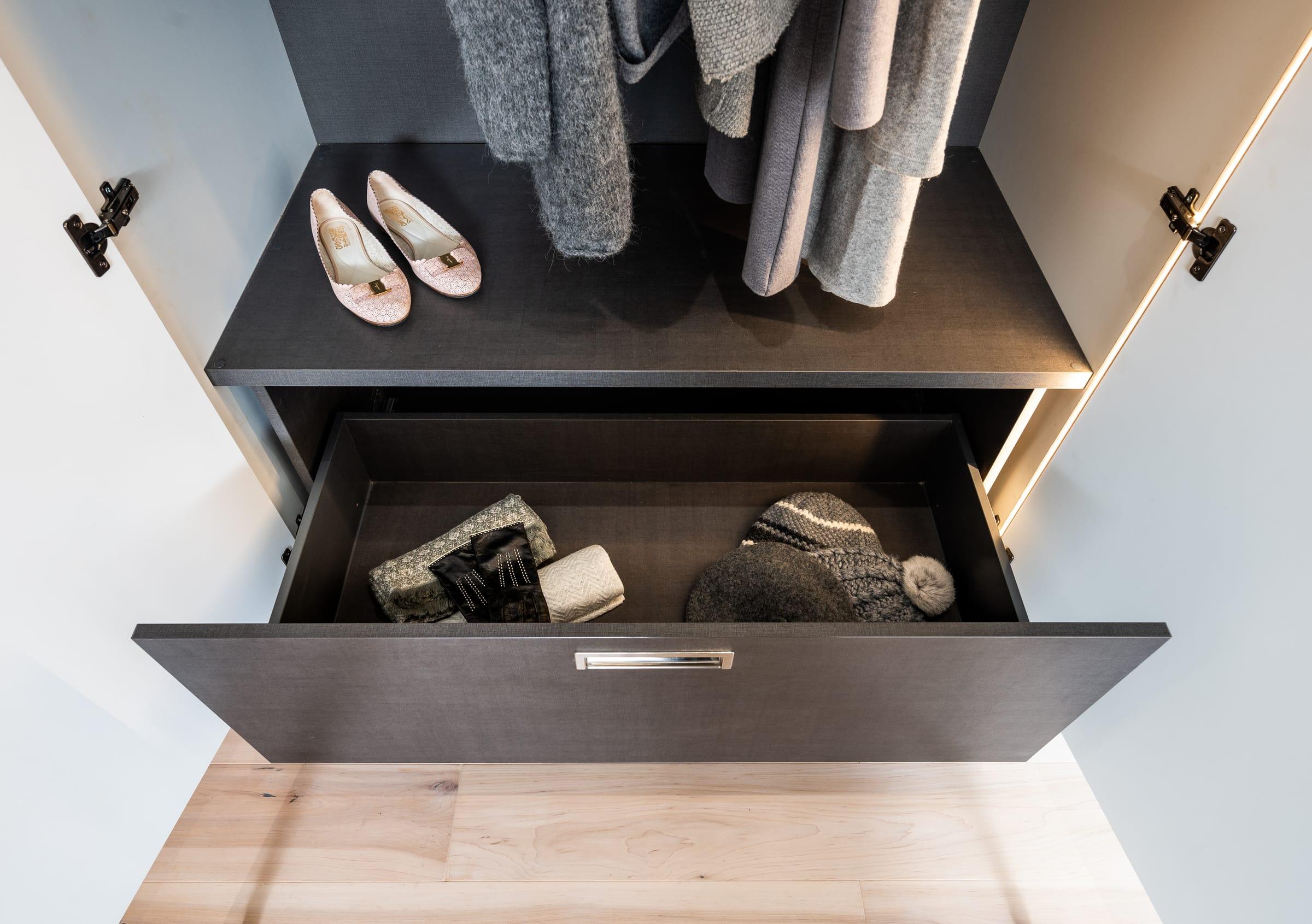 Dark drawer pulled out under hanging coats
