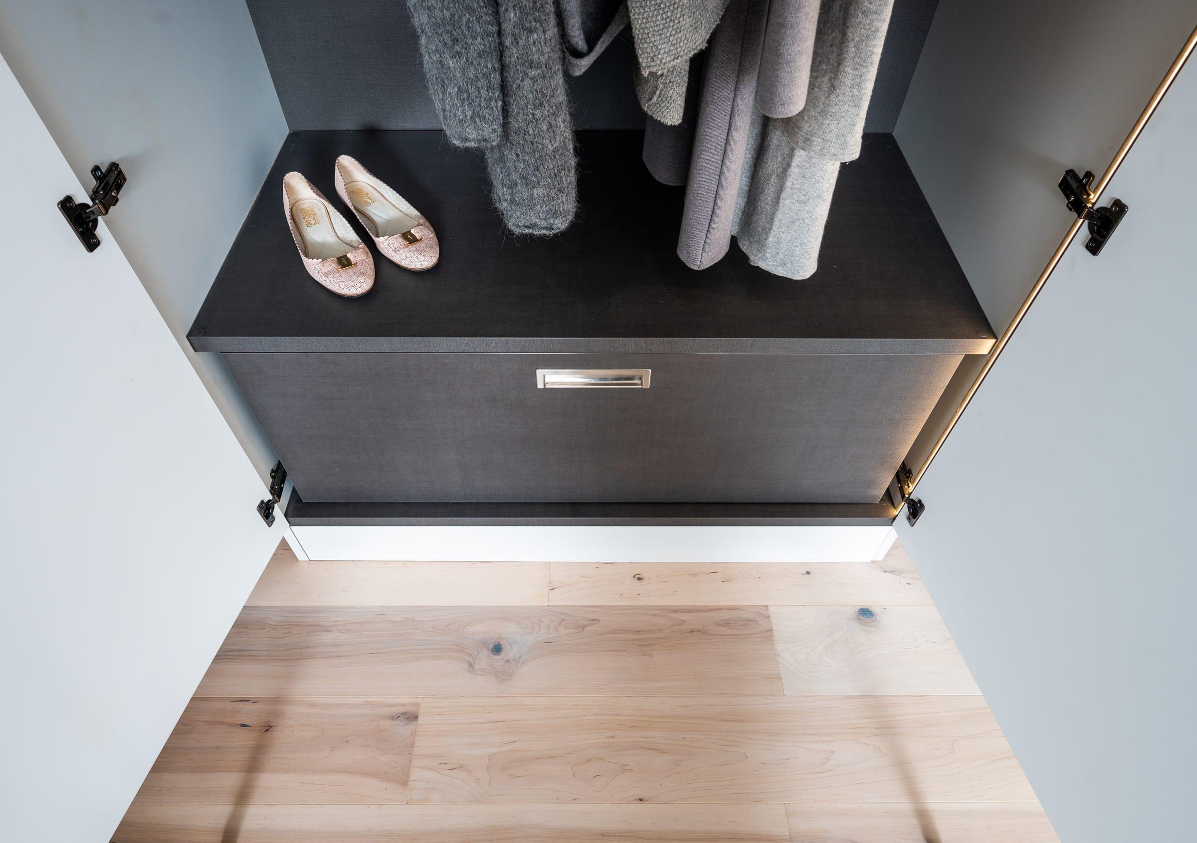 Dark drawer closed under hanging coats