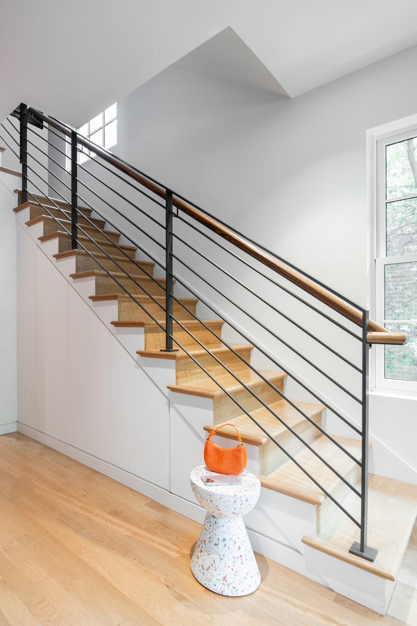 Staircase with a steel railing and a stool at its foot