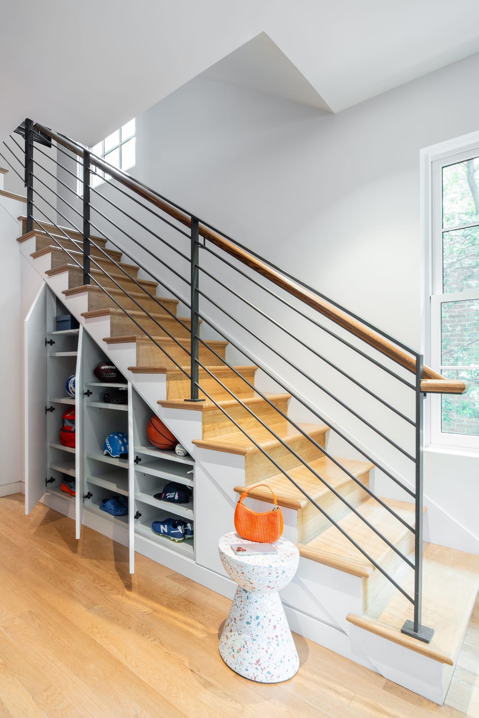 Open shelving built under a staircase with a steel railing