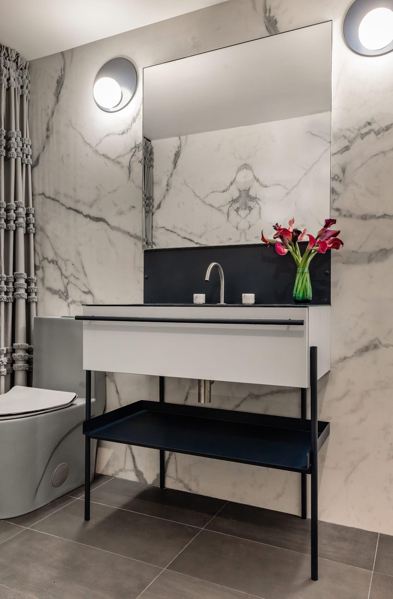 Washbasin on a black steel stand against marble walls